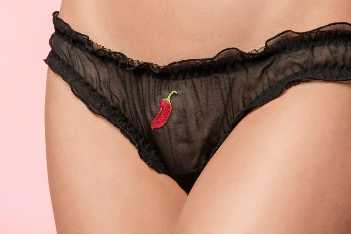 Close-up of the delicate red chili embroidery on fine black silk chiffon fabric.