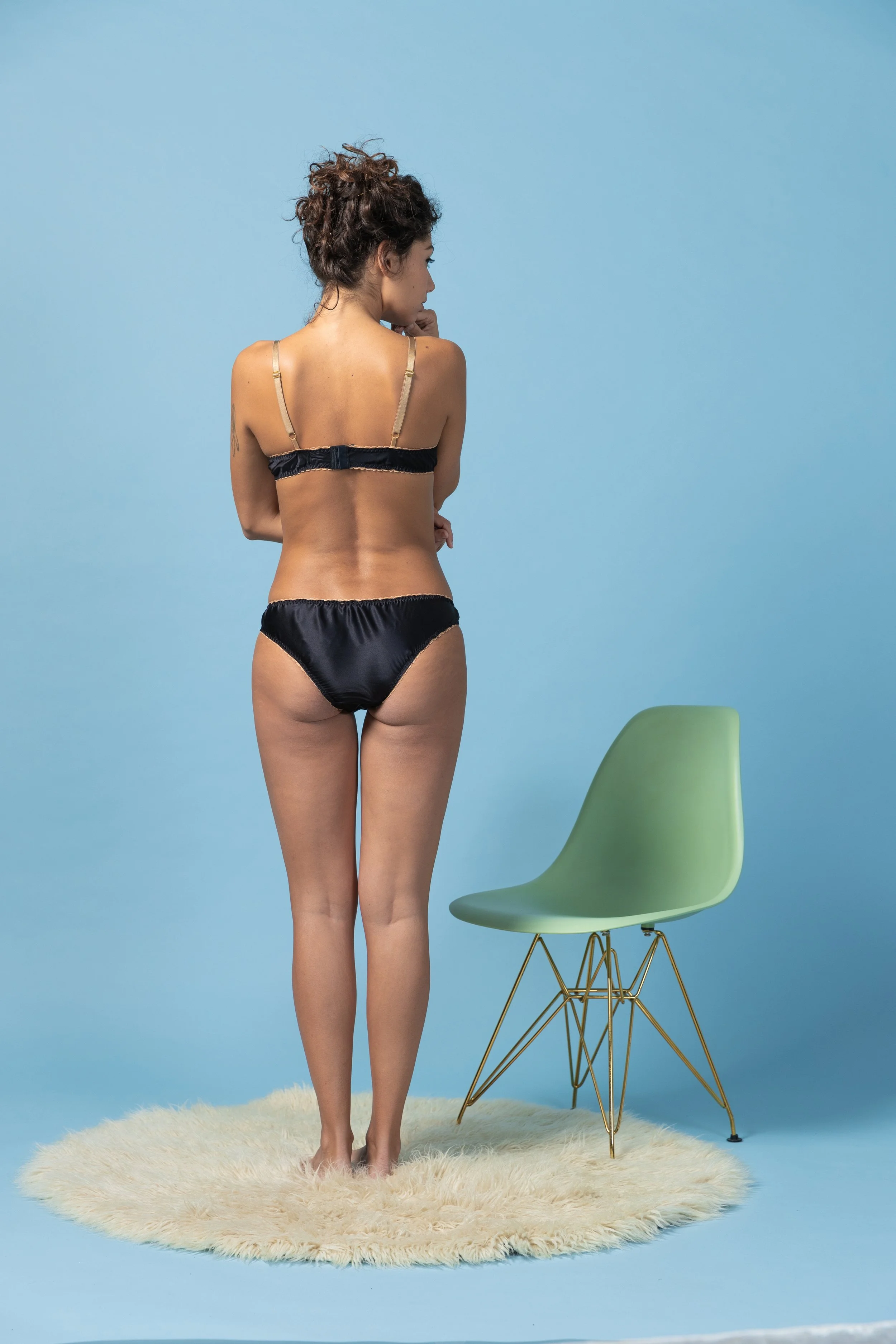 back view of Retro-inspired black silk satin lingerie set with champagne-gold trimmings on a model - Voilà le Vélo.