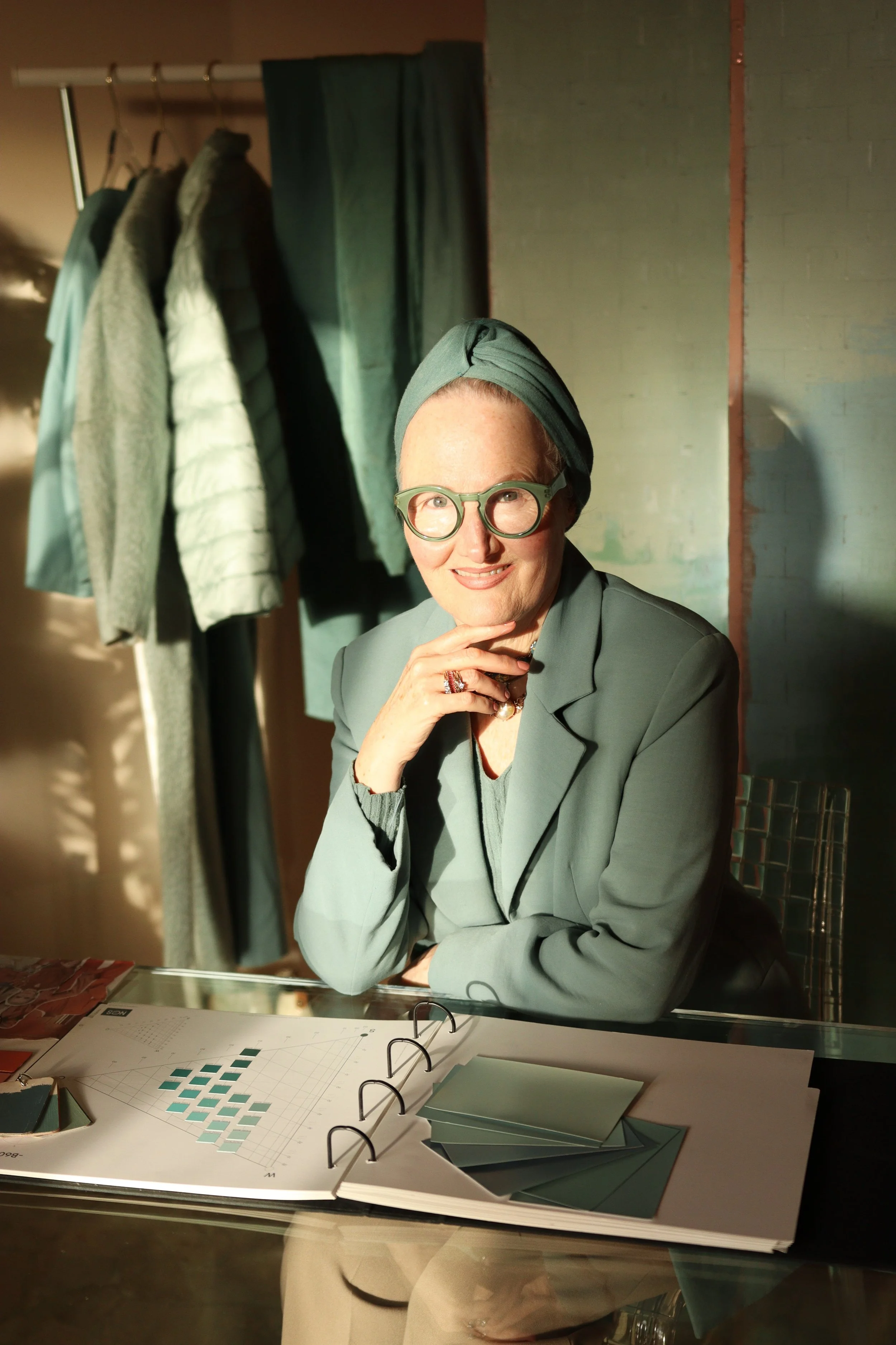 Lisa Maria Pippus wearing green at a desk with NCS color system book and cards, applying color theory to wardrobe planning