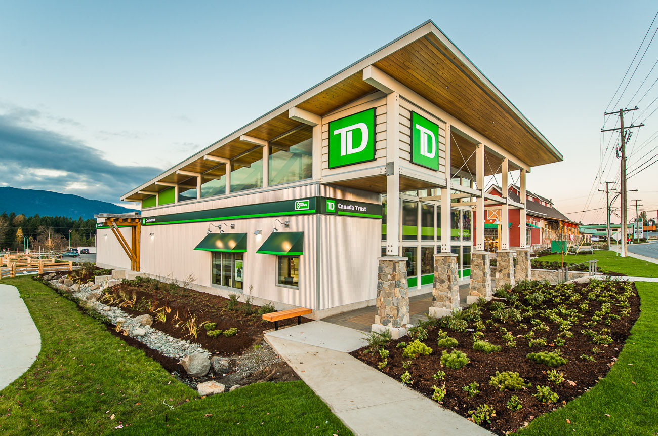 Corner elevation with rainwater bioswale, timber soffit, clerestorey glazing, and integrated signage.
