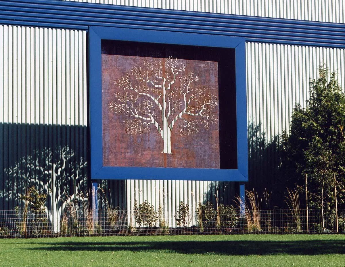  Decorative corten steel signage representing retained&nbsp;oak trees on site along Wellington Road and Nanaimo Parkway. &nbsp;When backlit at night against the corrugated metal cladding, the steel tree outline appears to move. 