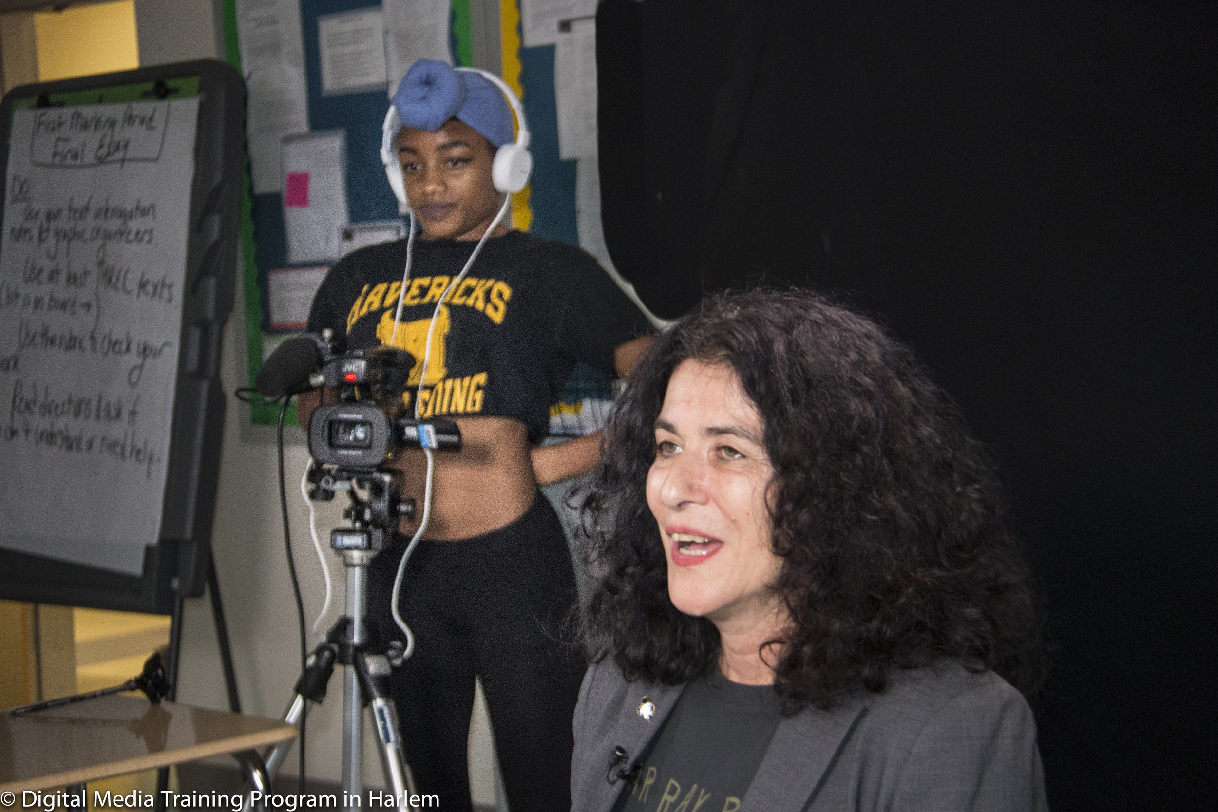 Photographer Janette Beckman being interviewed at New Explorers High School with student Aryon Holley on camera.