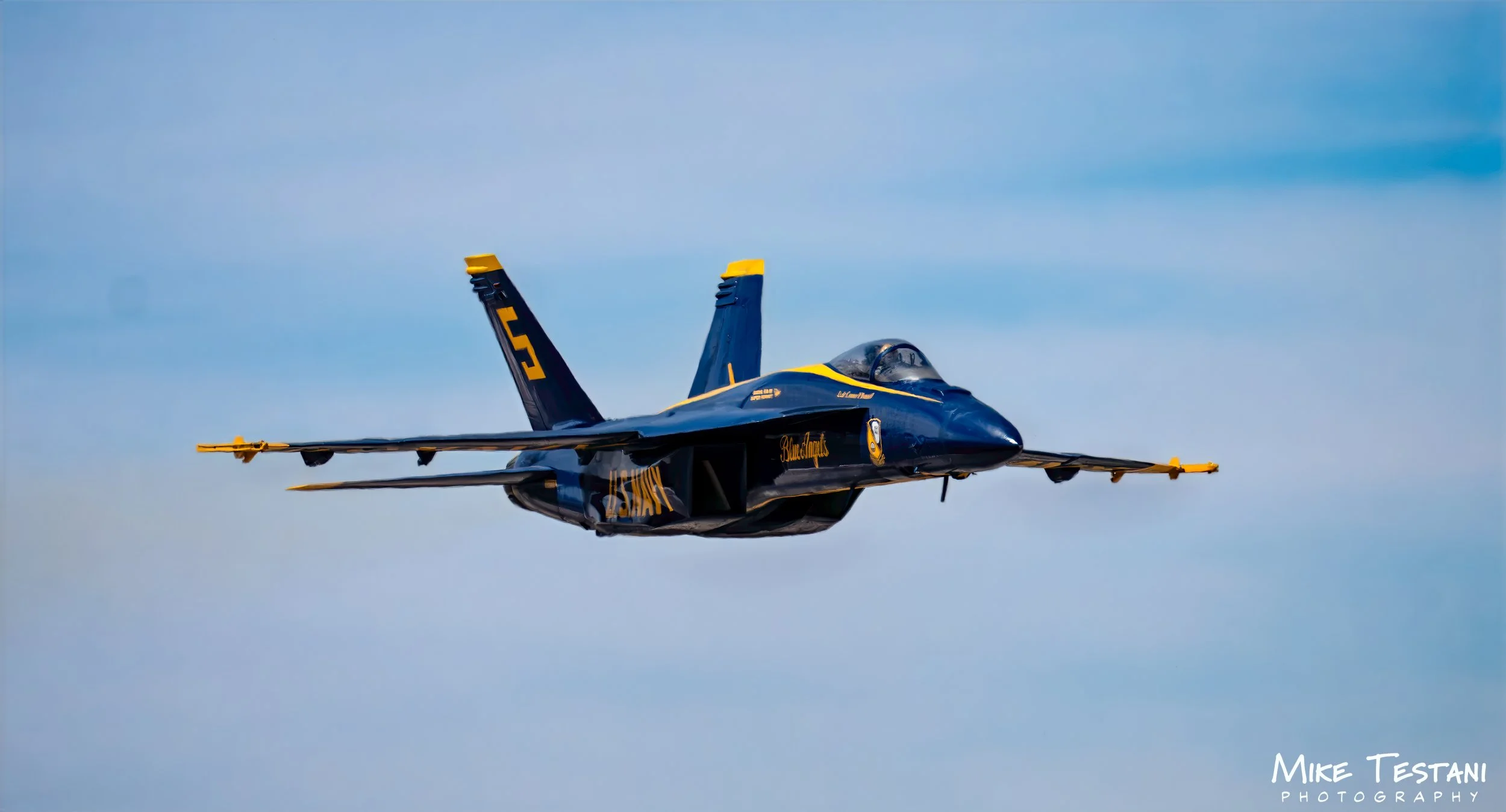 A blue and yellow fighter jet flying through the sky.