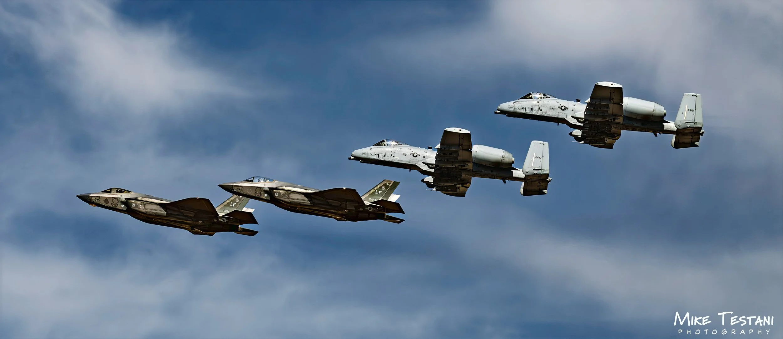 Four military fighter jets flying in formation against a cloudy sky.