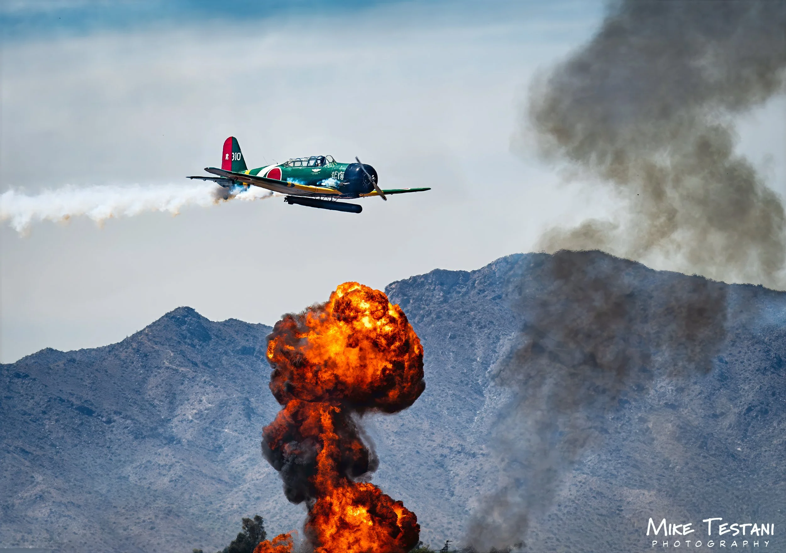 An airplane flying over a mountain, releasing smoke, with an explosion below on the mountain.