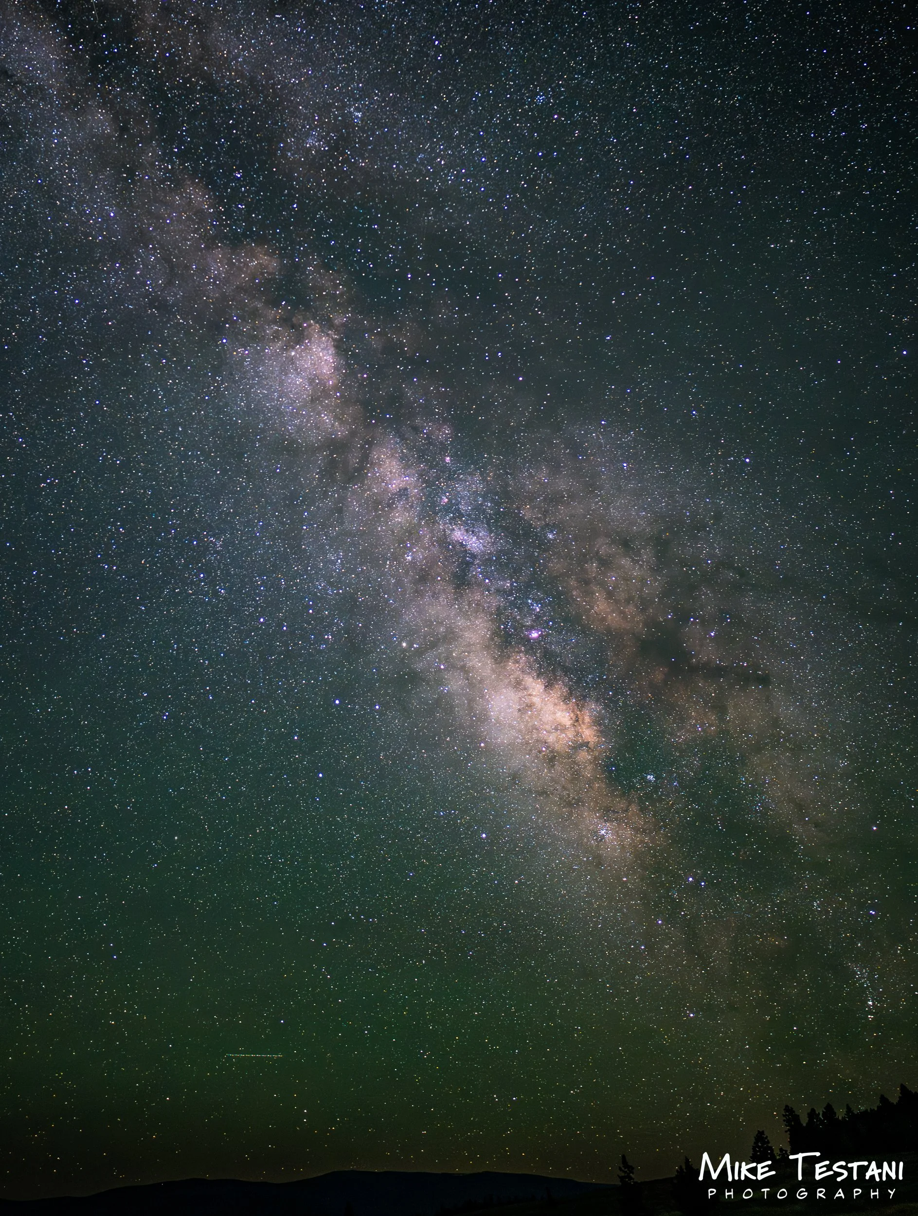 A night sky filled with countless stars and the Milky Way galaxy visible above dark mountain silhouettes.