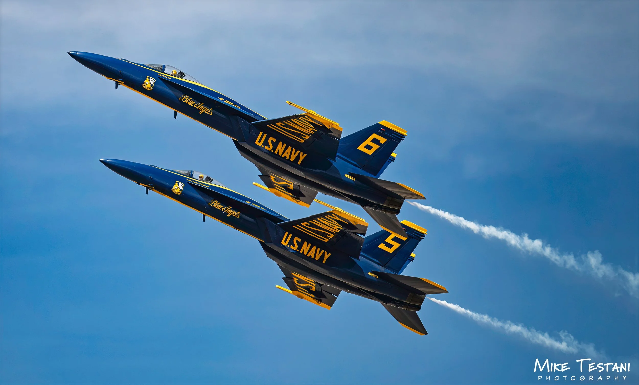 Four U.S. Navy Blue Angels fighter jets flying in tight formation against a blue sky.