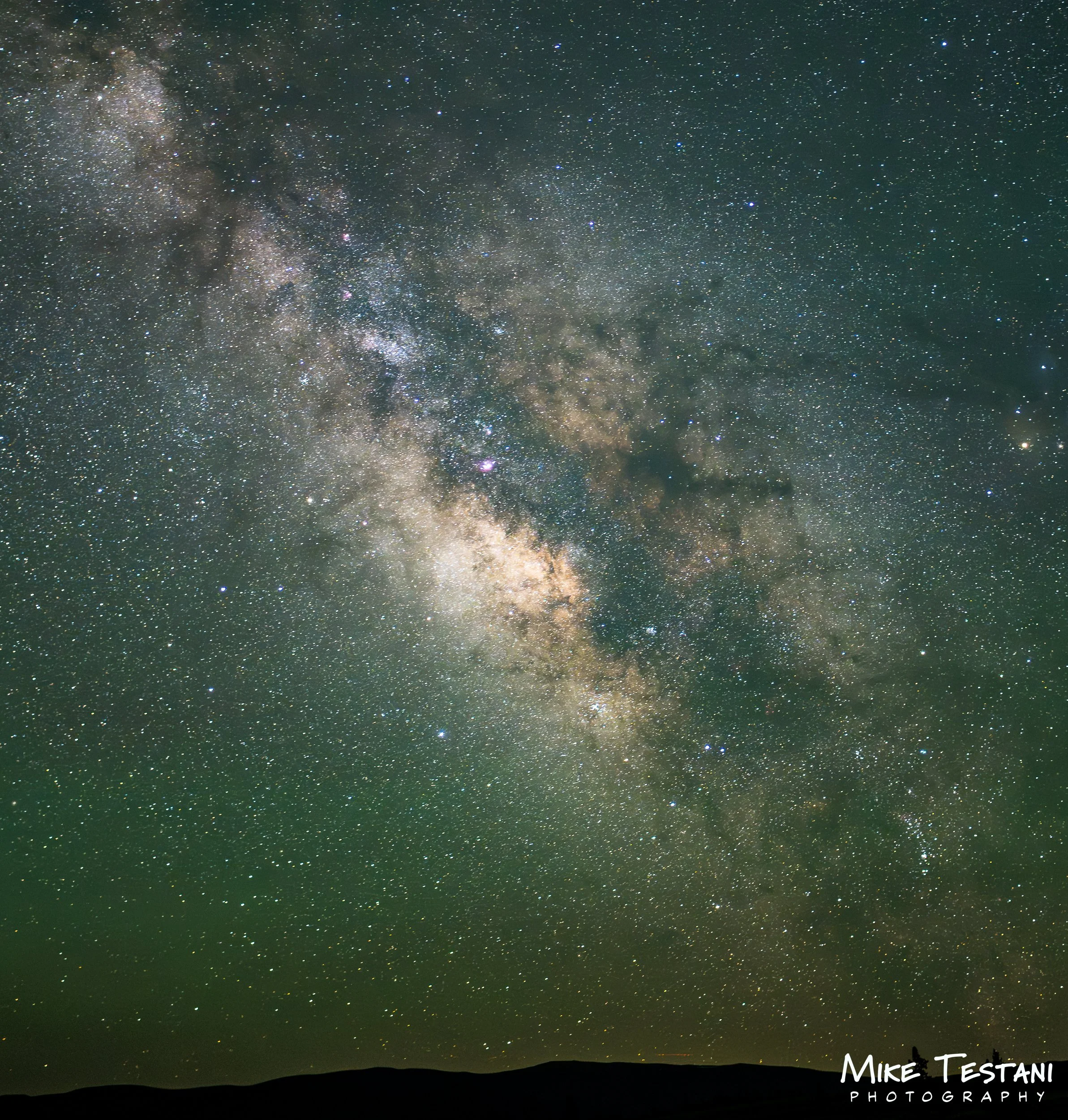 Night sky filled with stars and the Milky Way galaxy visible over a dark landscape.