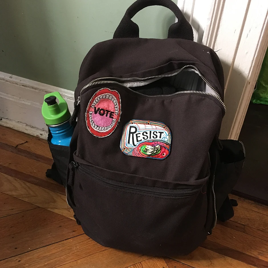 The VOTE patch was designed by Nancy Chunn and produced by We Make America . I made the RESIST plaque. Earring, clay, paint on wood.