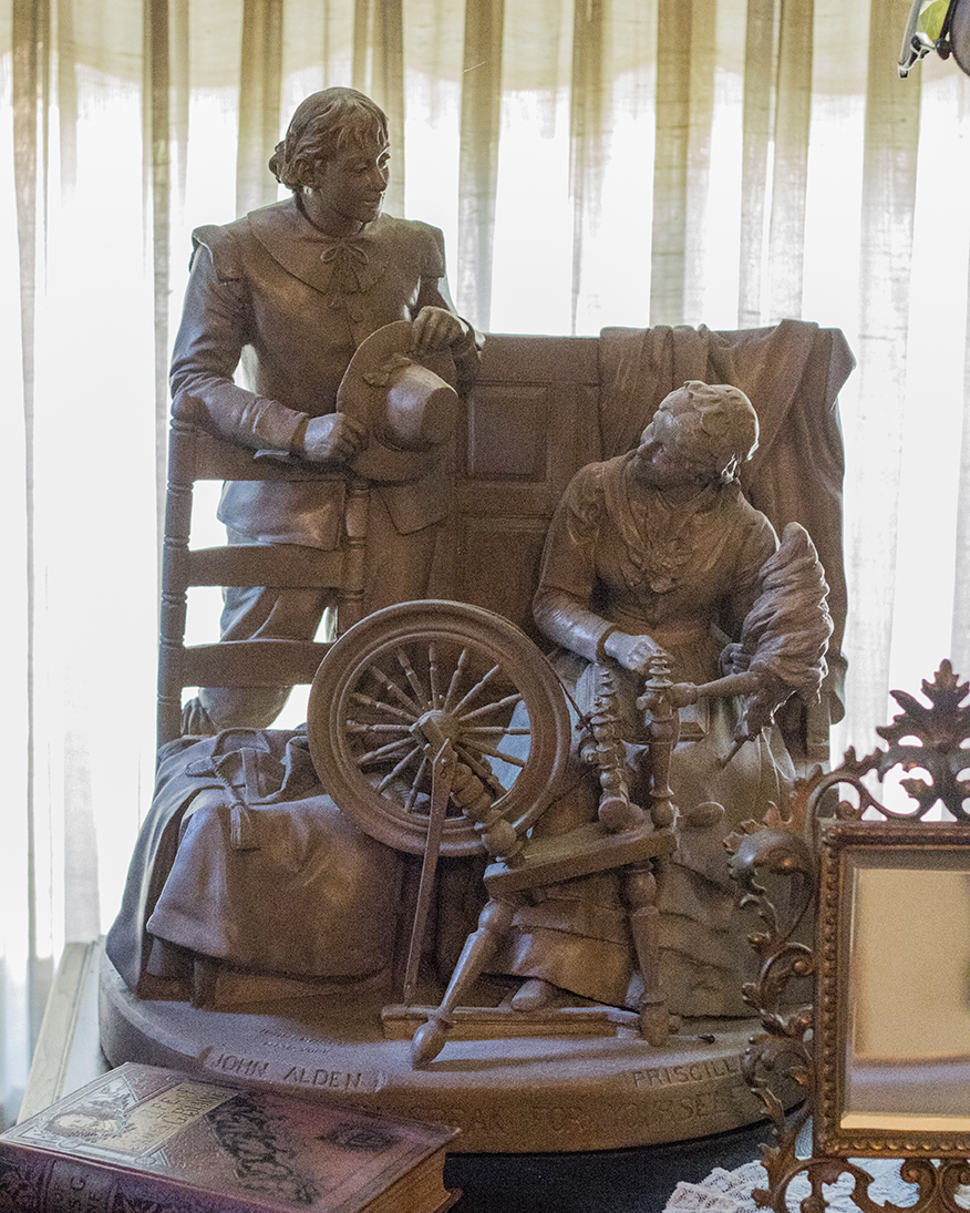 This was a statue of an older style of spinning wheel, complete with the wool being held on the distaff. Note that she is reading a book on her lap as well.
