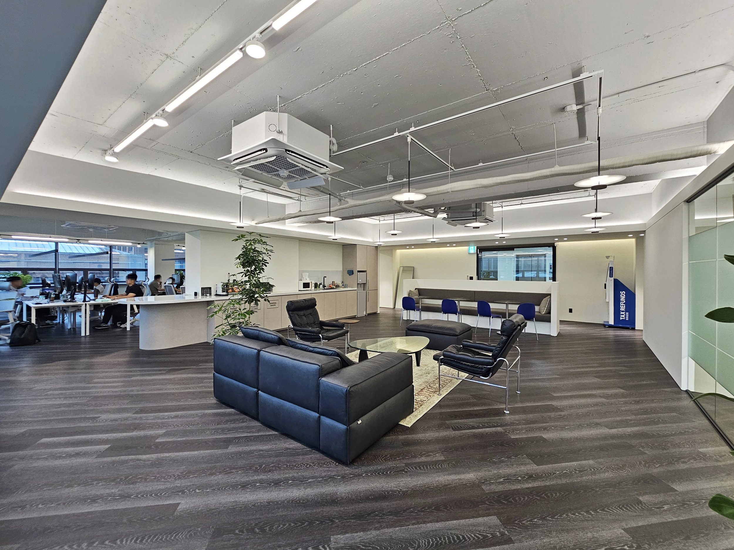 Quarter view of the lounge area with the entrance and workstation zones visible in the background