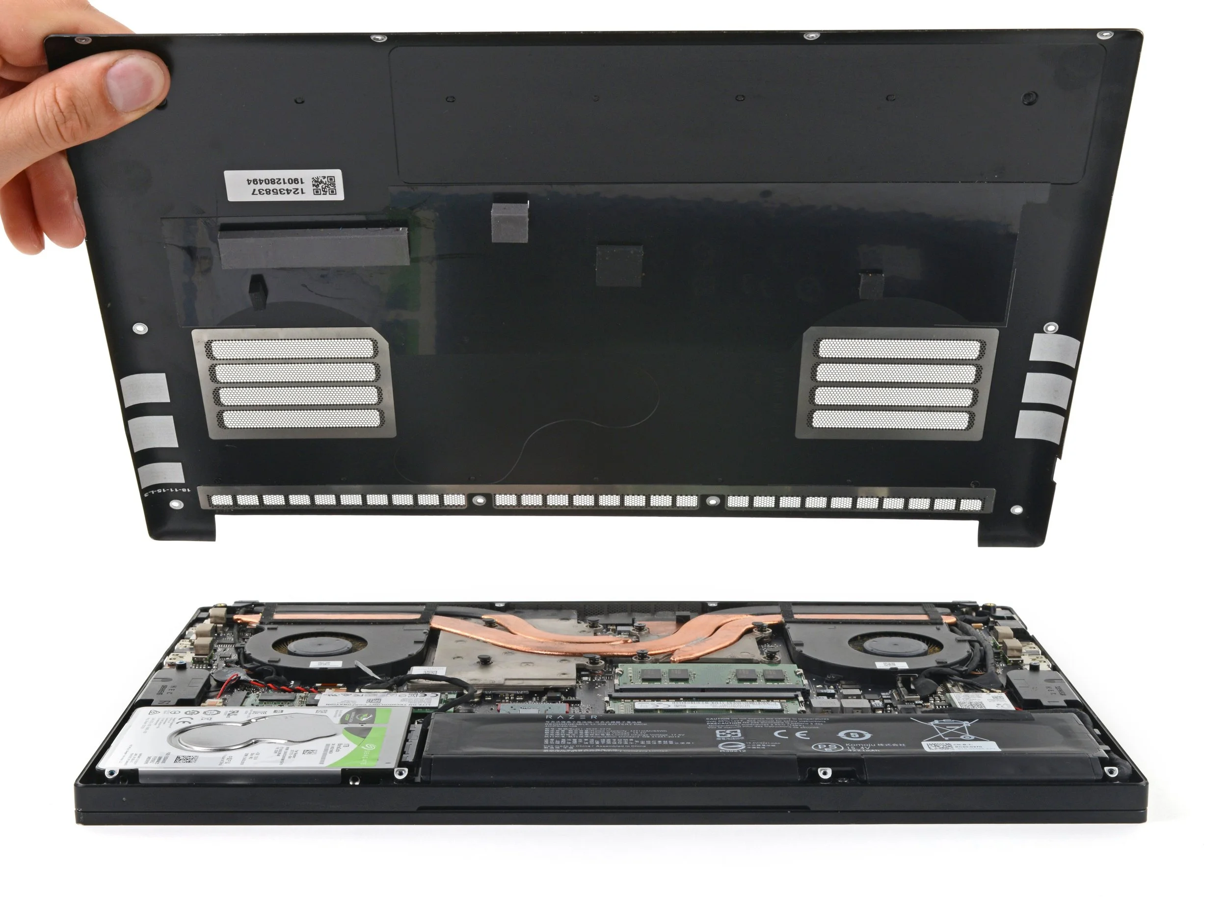 Open laptop with the bottom cover removed, revealing internal components including hard drive, cooling fan, and circuit board.