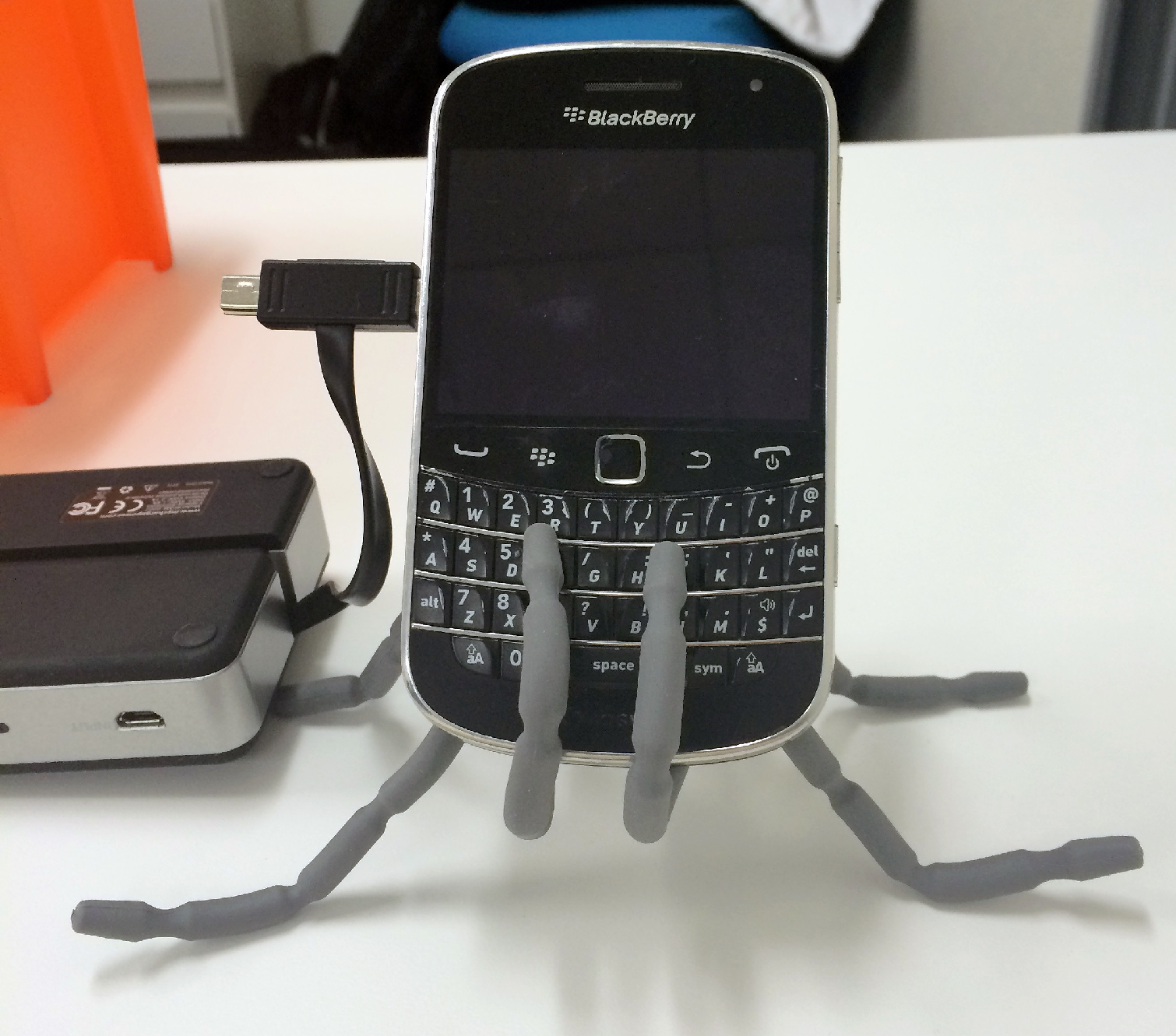 Holding up a blackberry while it is being charged by an external battery
