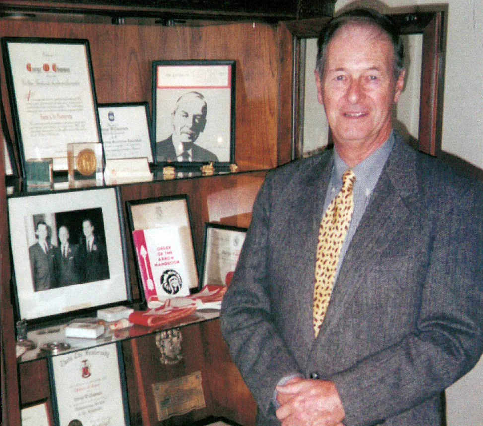 George W. Chapman Jr. (Omega/Penn State '49) stands before a display case at the International Headquarters in which are displayed many mementos and personal artifacts of his father, George W. Chapman (Omega/Penn State '32)