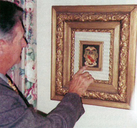 Brother Chapman admires a coat of arms patch that is on display at the International Headquarters. Suit patches of this sort were worn very fashionably in the 1950s and 1960s on a blue blazer. Shortly after his visit to the International Headquarters, Brother Chapman gave one of his own Theta Chi suit patches for display in the Chapman Library. The gold leaf frame, which contains the patch being admired by Brother Chapman, was crafted in 1856, the year of the Fraternity's founding