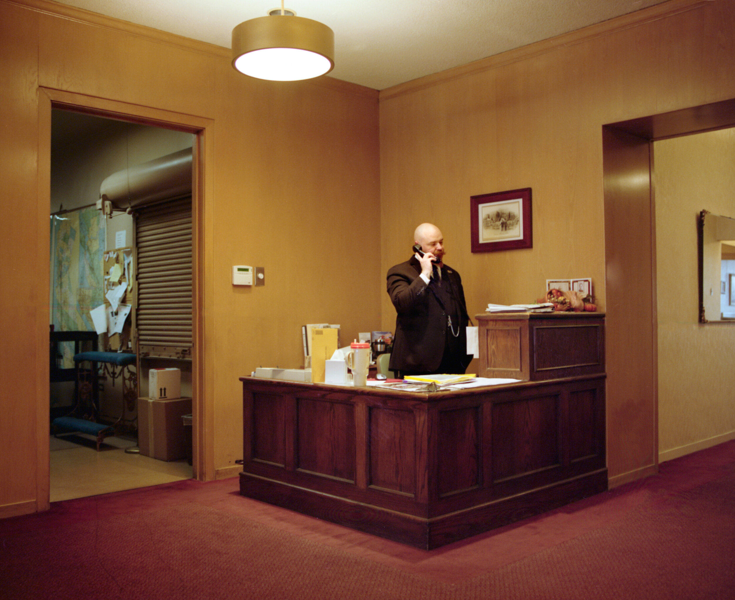   Edward at the front desk, Valente Marini Perata &amp; Co. funeral home , 2016, archival pigment print 