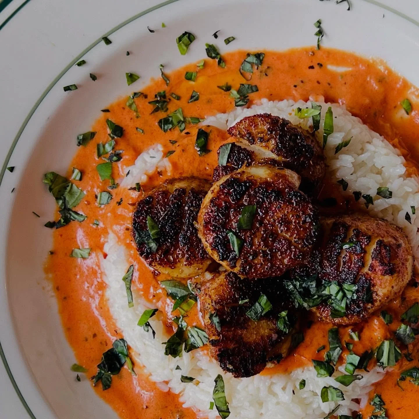 🔥 Spice, sear, and sauce&mdash;perfection on a plate.

Blackened Cajun scallops resting on a bed of fluffy white rice, bathed in a silky roasted red pepper cream sauce. Bold flavors, perfectly balanced.

Now serving at The Ovalon&mdash;come get a ta