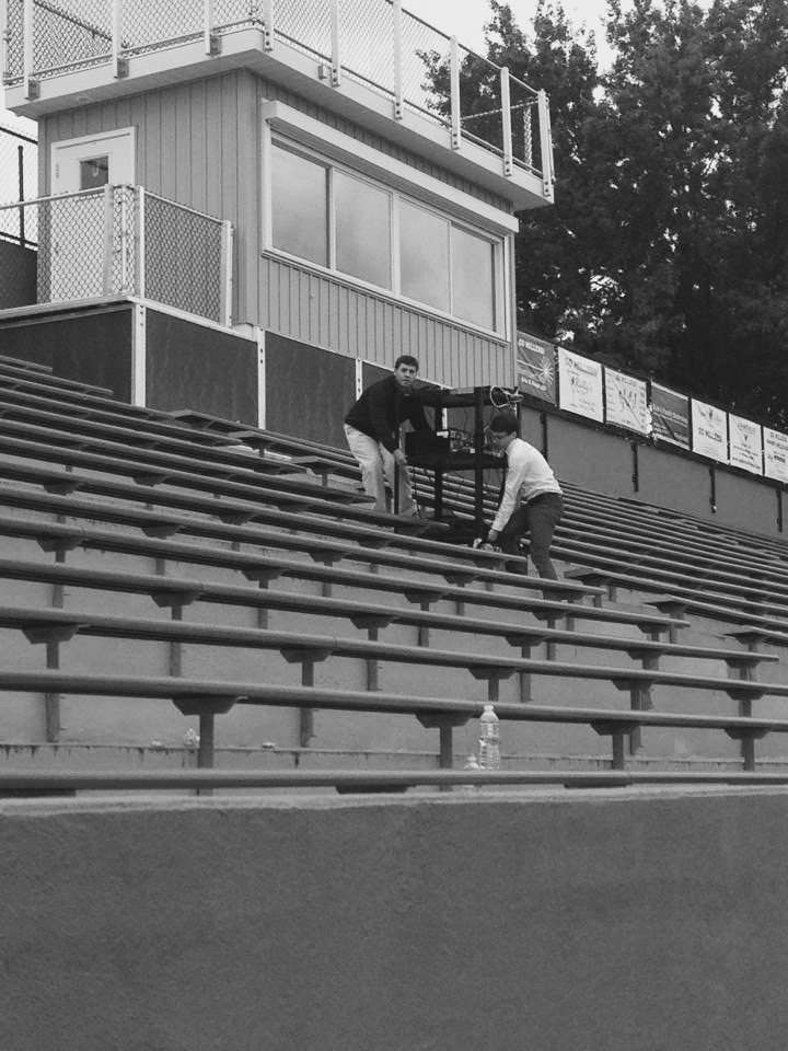 Josh (abeam) and I (astern) carrying a card of equipment up the bleachers.
