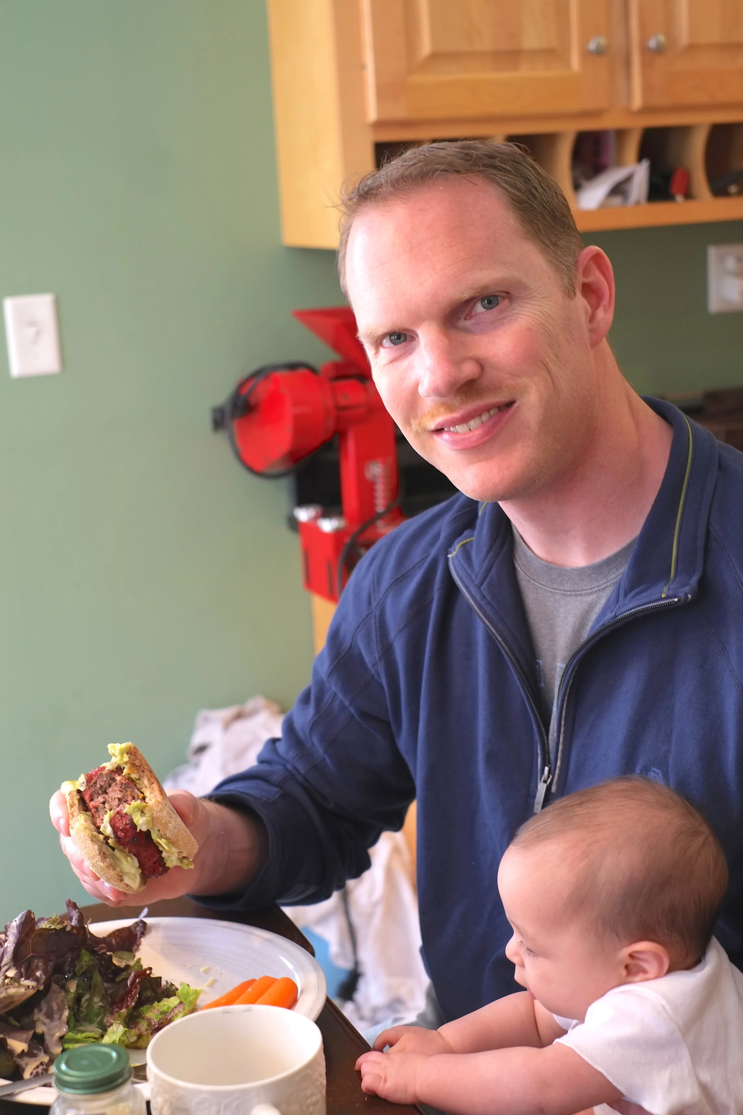 Tim holding Priscilla and enjoying his delicious burger.