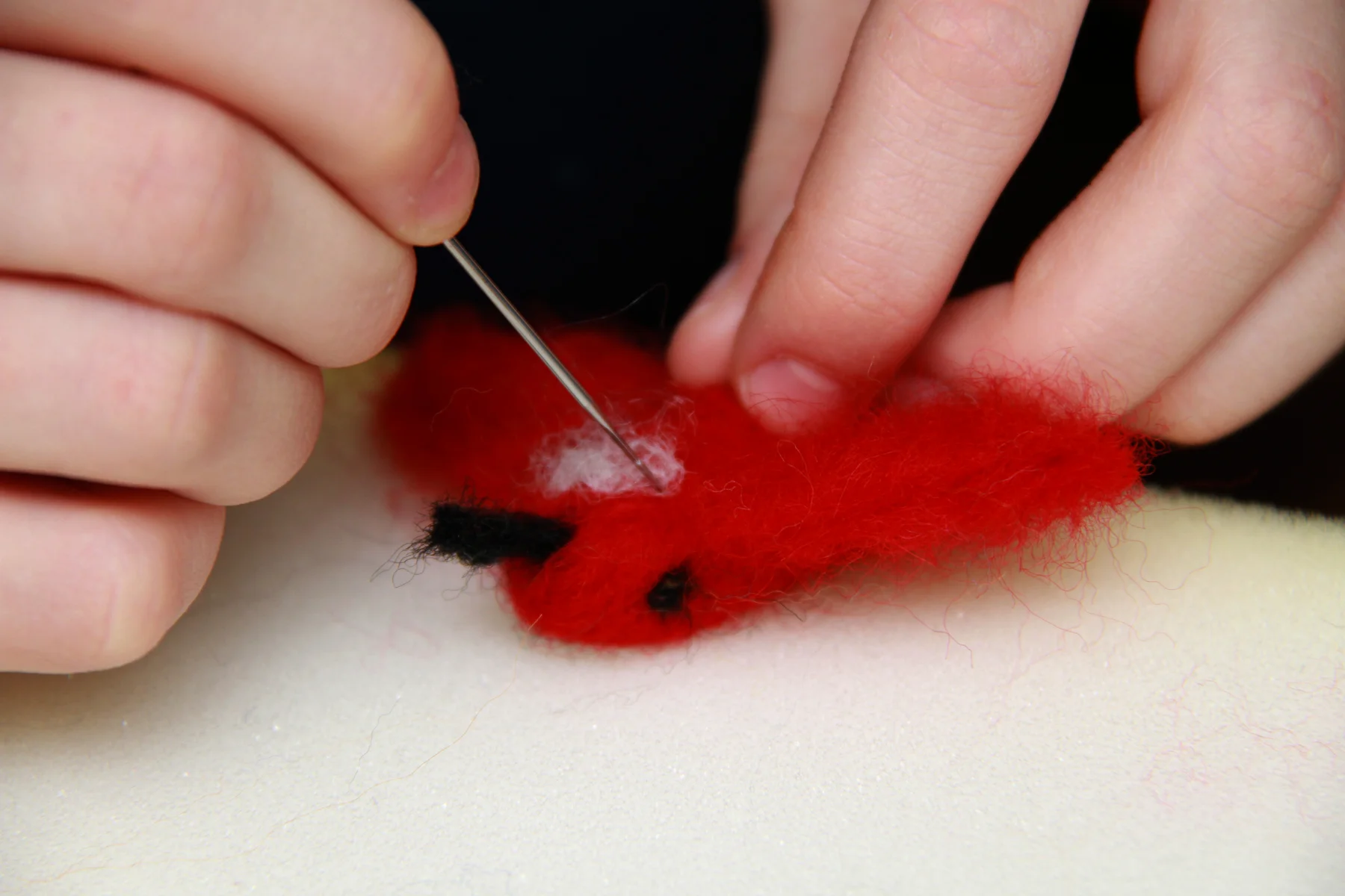 This student is carefully using a barbed needle to sculpt this beautiful bird out of un-spun wool.