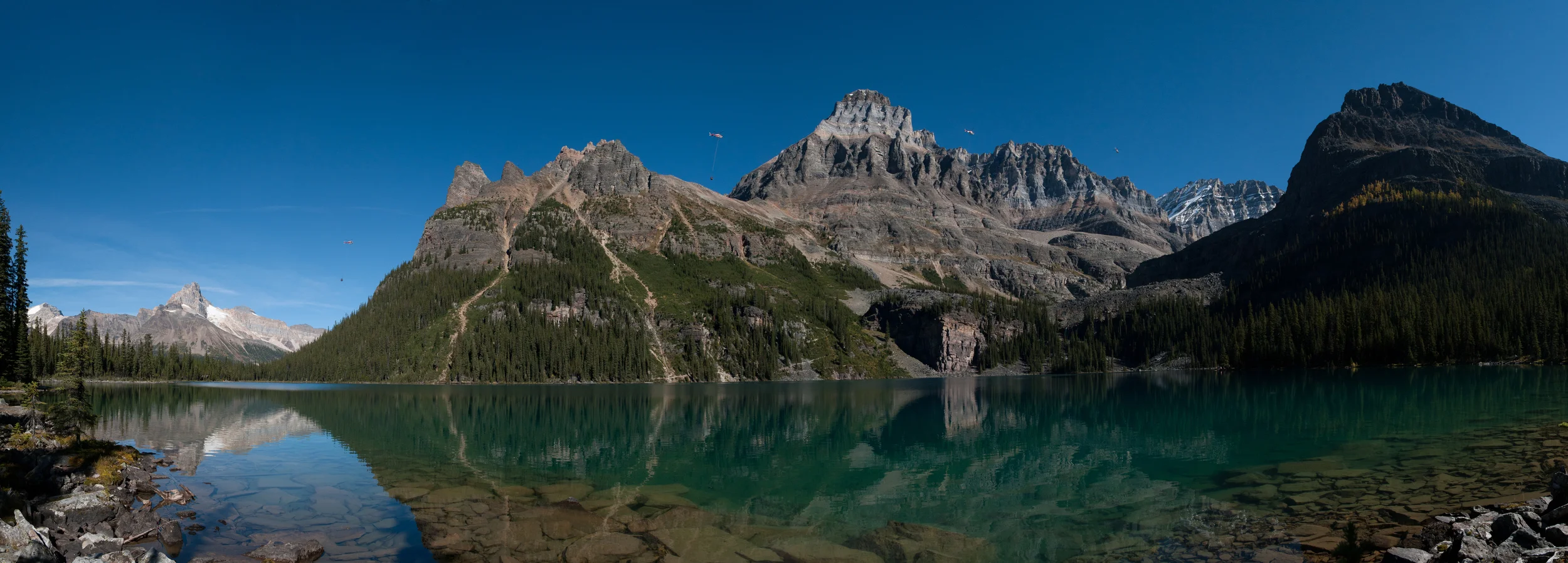 Panoramic photograph of Lake O'Hara capturing a helicopter at four different positions along it's flight to Abbot Pass Hut.