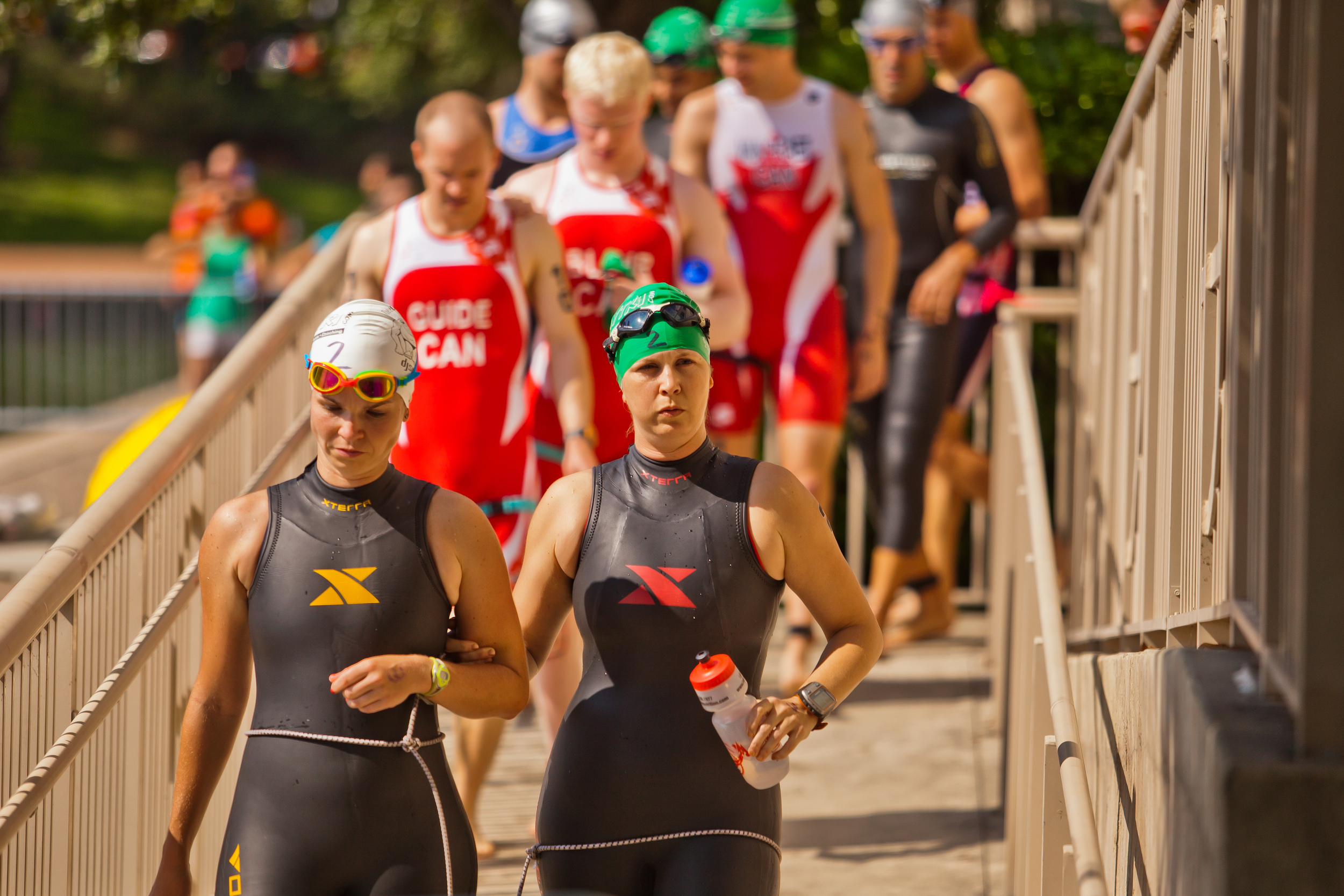  Amy Dixon (right, in green cap), a visually impaired sommelier and triathlete, is guided to the start of the swim portion of the 2014 Dallas Panamerican Triathlon Confederation (PATCO) Triathlon Pan American Championships by her guide Caroline Gayno