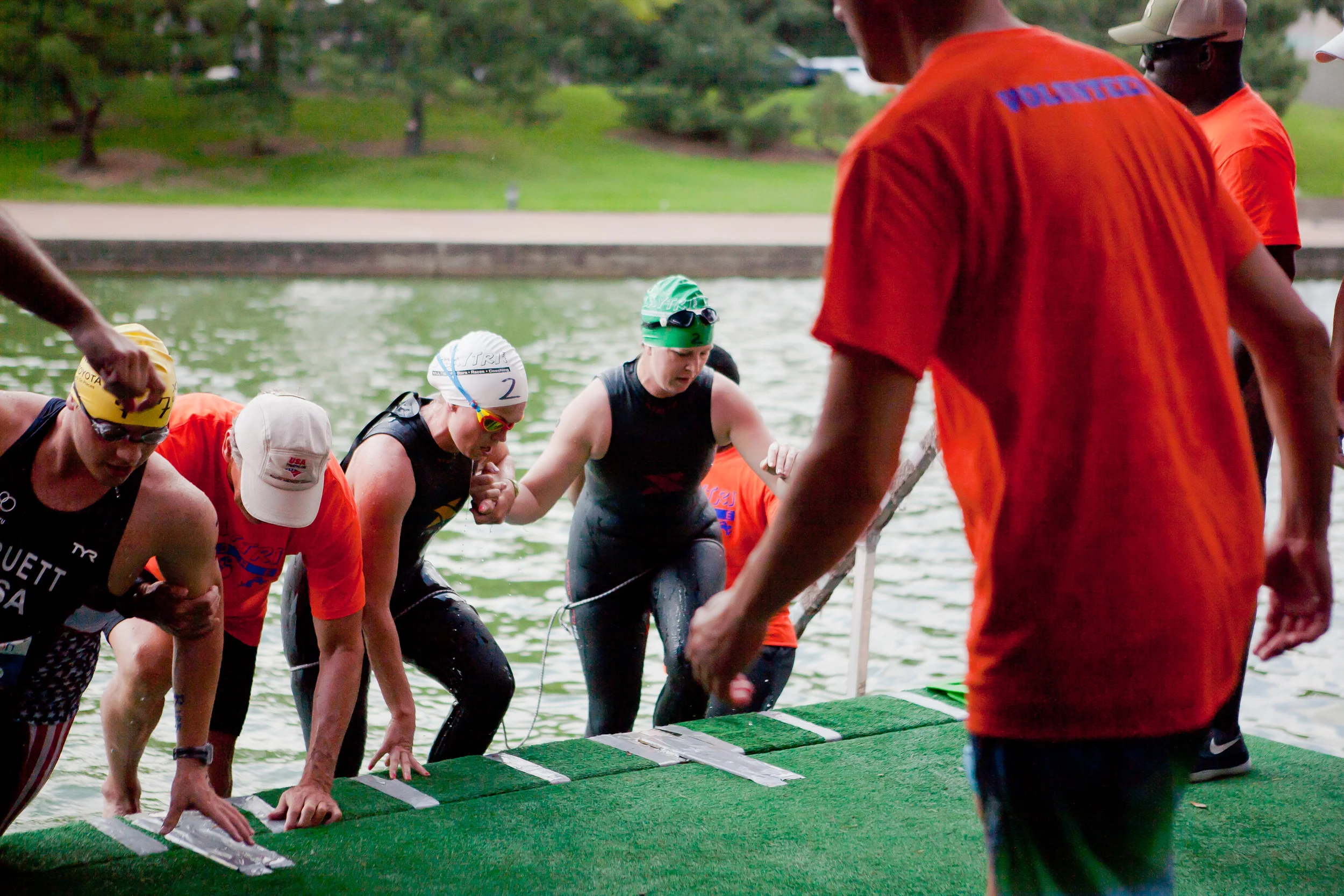 Amy Dixon (center, in green cap), a visually impaired sommelier and triathlete, is guided out of the water after the swim portion of the 2014 Dallas Panamerican Triathlon Confederation (PATCO) Triathlon Pan American Championships by her guide Caroli