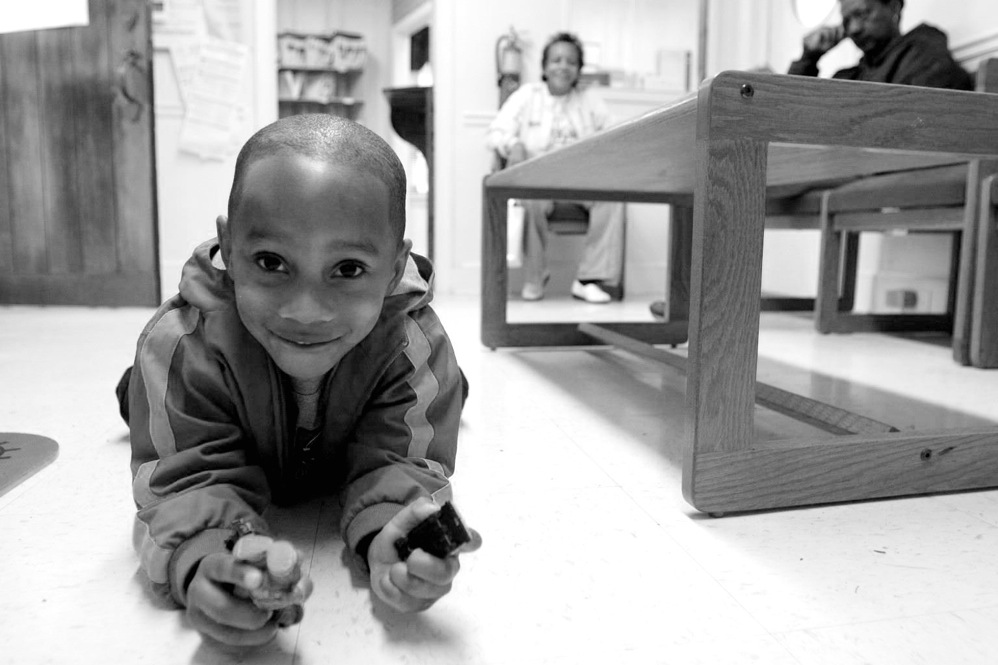 Marcus, 2, plays with toy cars in the waiting room as he waits for his mother to return from her exam.