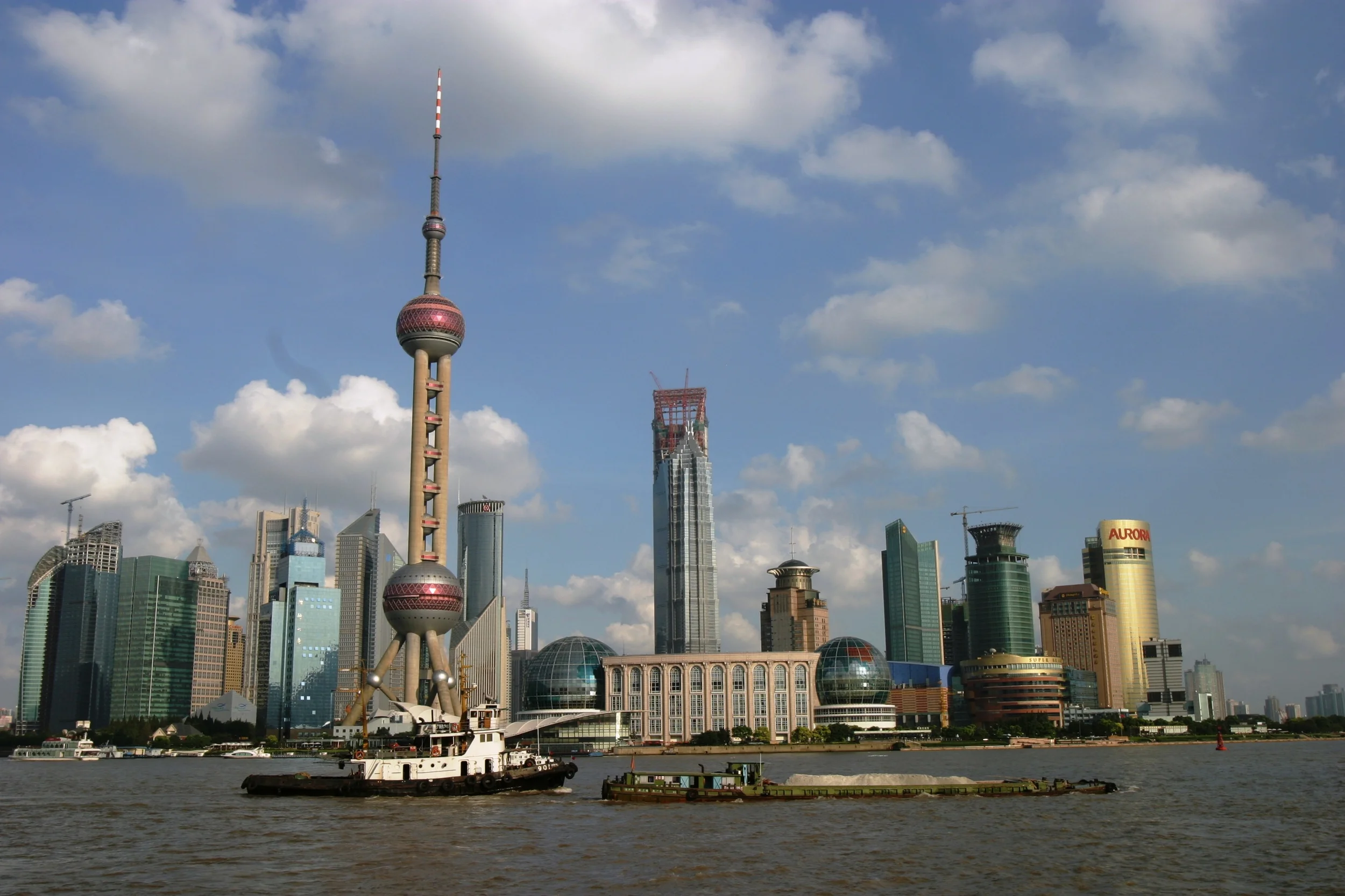 Boats float down the Huangpu River in downtown Shanghai, China overlooking the city’s Pudong district. The Oriental Pearl TV Tower rises above the rest of Shanghai’s skyline. 