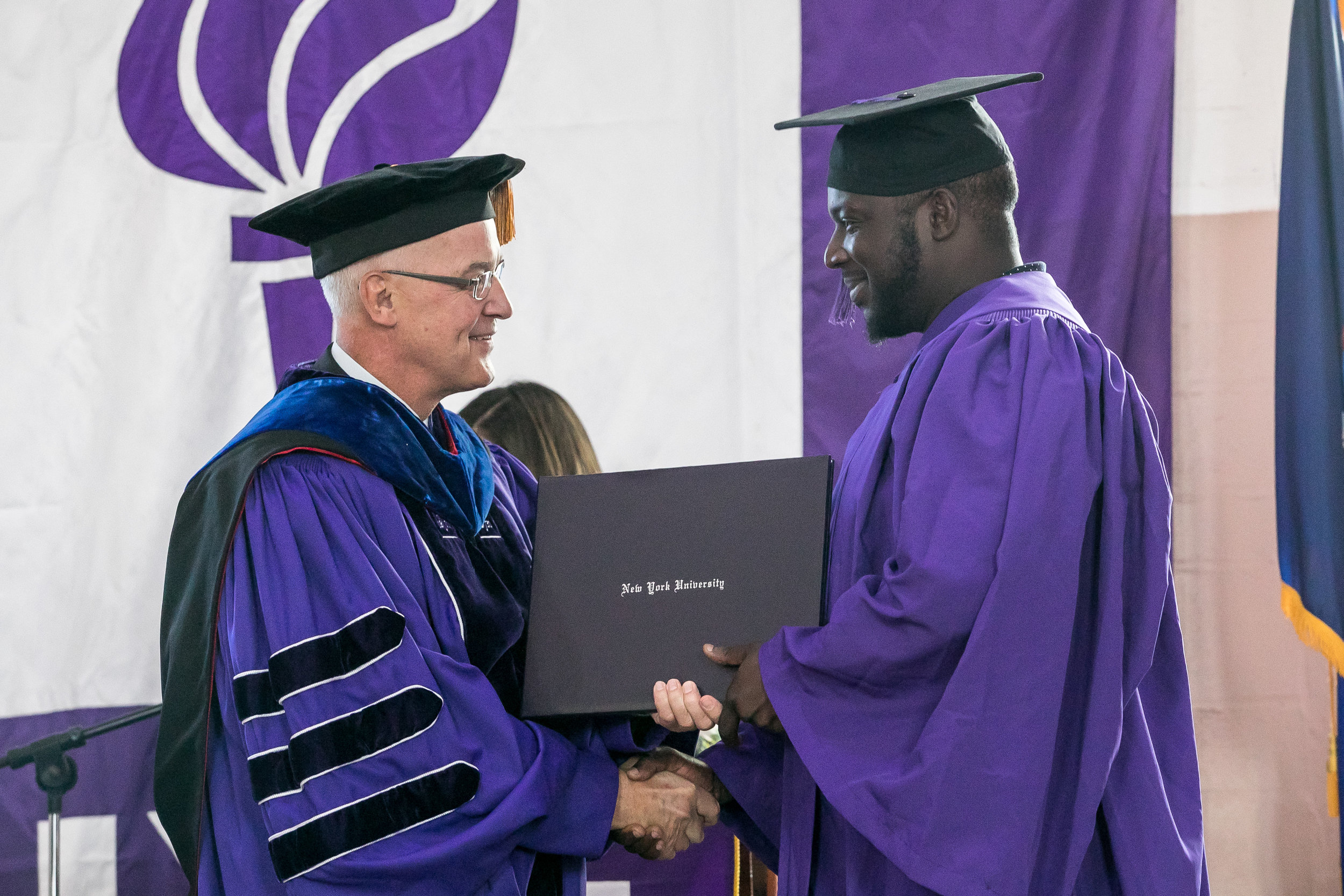  Ryan Burrell receives his diploma from President Hamilton. The graduates earned Associate of Arts Degrees from New York University in Liberal Studies. 