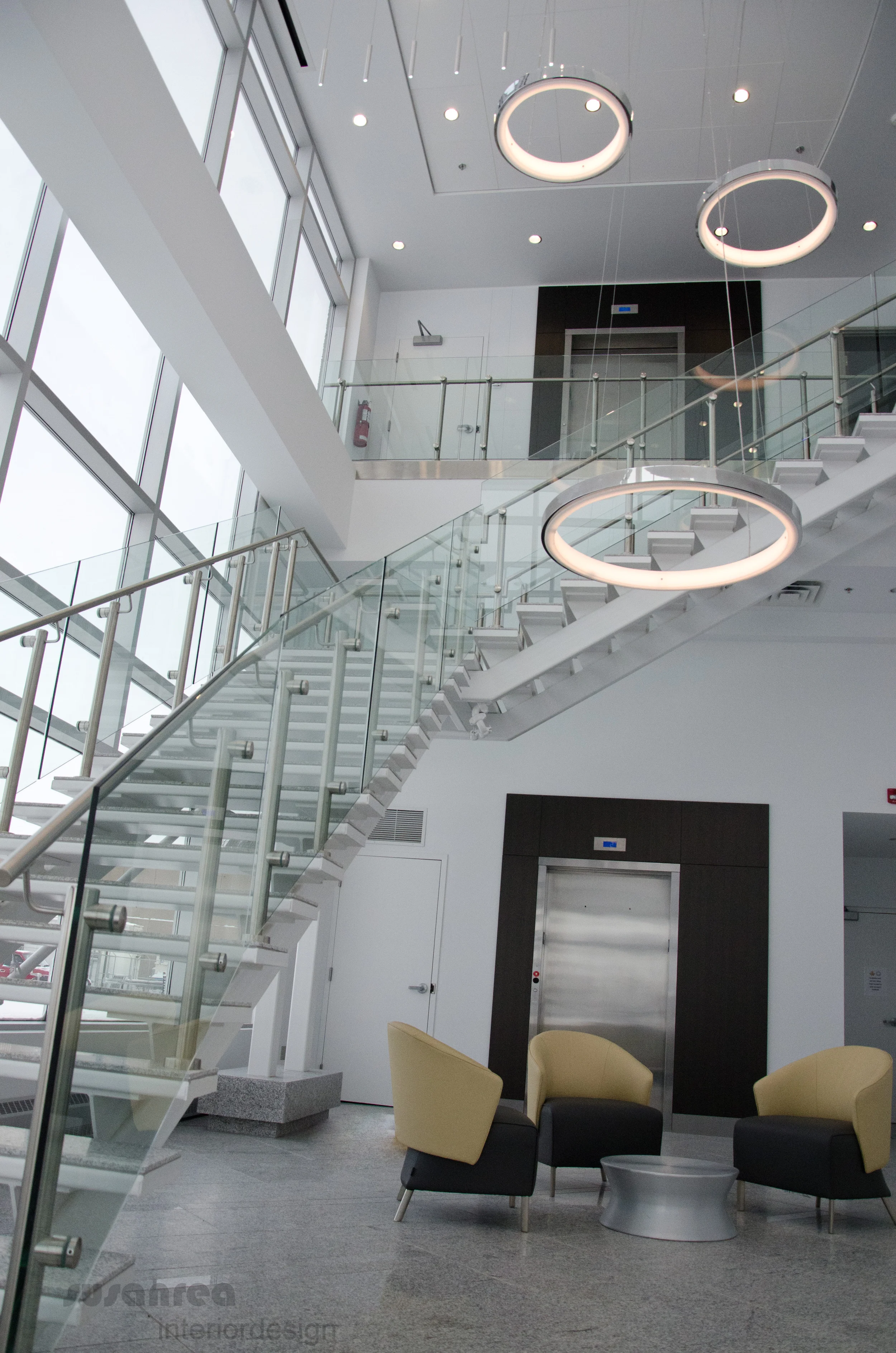  White walls, ceiling and stairs allow the flood of light from the window wall to play around the space and emphasize the curved forms of the mezzanine above. LED pendant lighting by Sattler . Furniture by Nienkamper