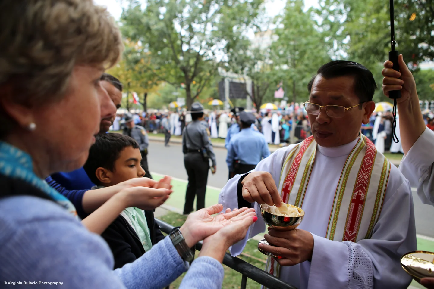 Un sacerdote distribuyendo entre la multitud hostias, o pan de comunión. 
