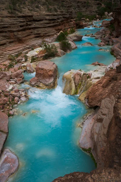 Ribbon of Life.. Photograph by Terrence Robertson-Fall. Havasu Creek snakes down through the orange, dry rocks of the Grand Canyon. Along the way, it picks up limestone, giving the water a rich shade of topaz. It is life itself, out in the parched reaches of the desert.
