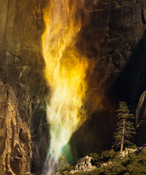 Firetwist. Photograph by Terrence Robertson-Fall. Blazing like a twister of fire, the whispy, late fall Yosemite Falls swims through a sunlit rainbow in Yosemite National Park. At this time of year, the water flow is at it's lowest, and the falls aren't much more than a mist that are easily blown about by the breezes.