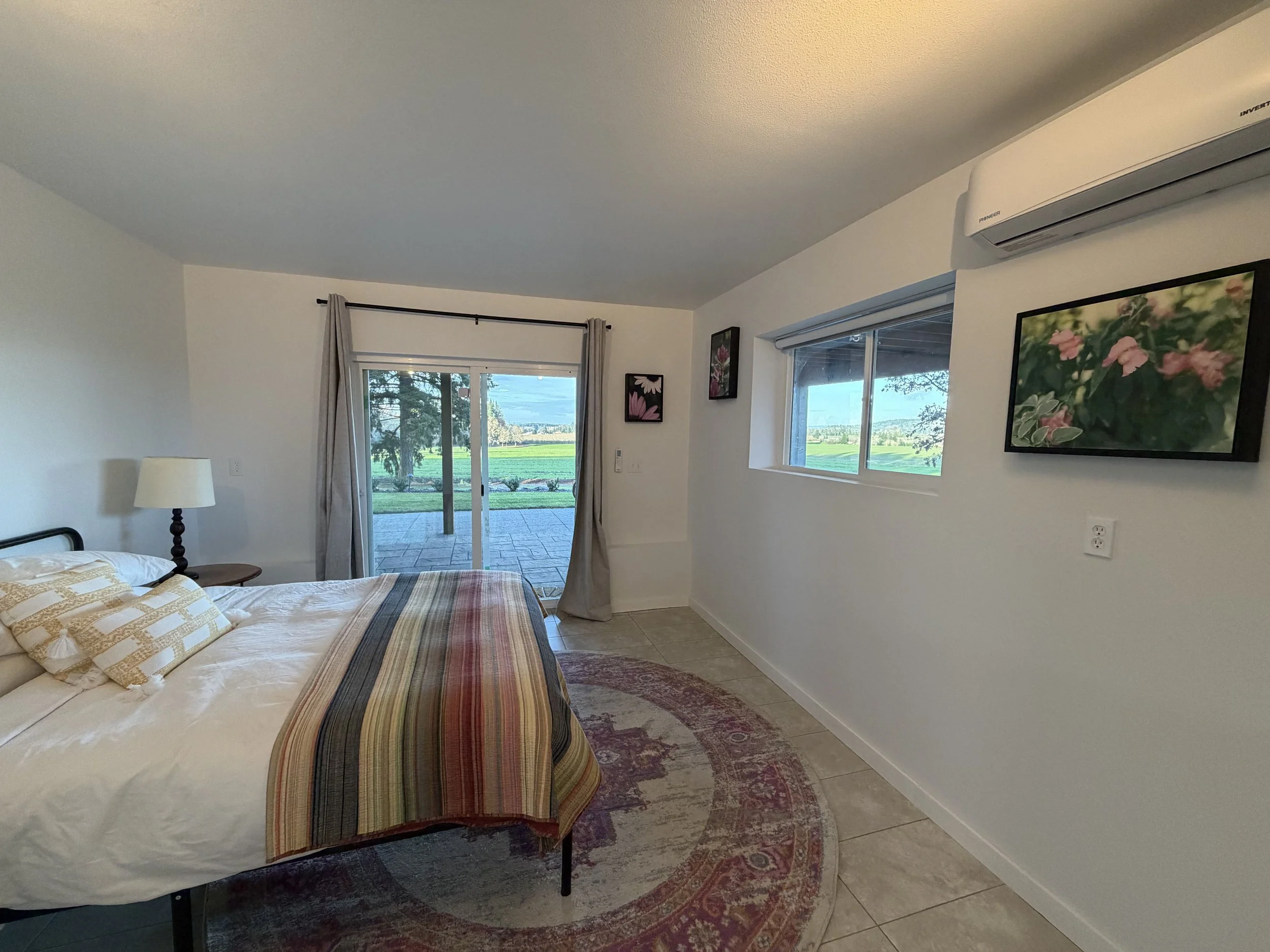 Bedroom with bed, artwork, sliding glass door, window, air conditioner, and outdoor view