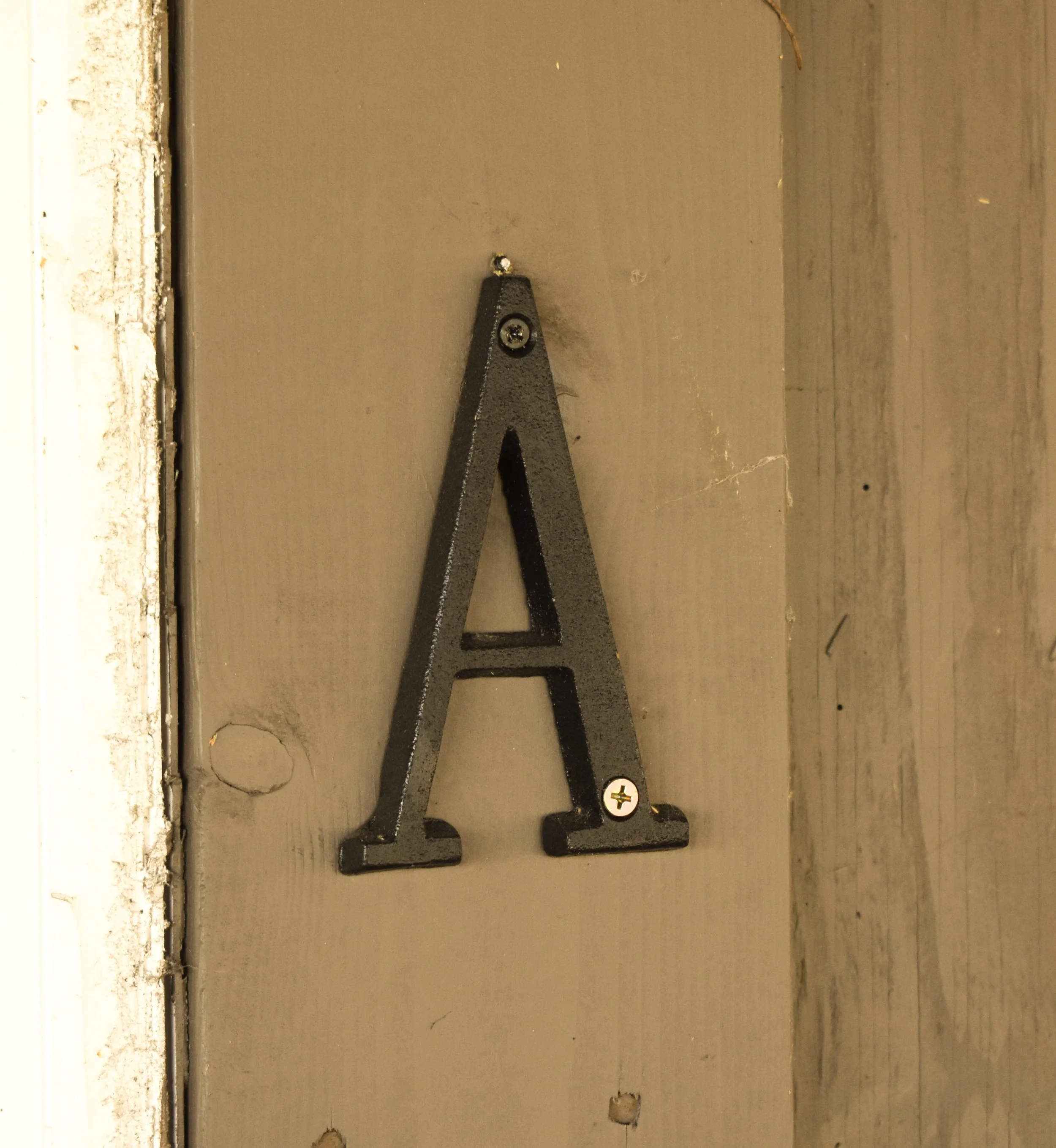 Close-up of a black metal adjustable wrench resting on a beige wooden surface with visible grain and cracks.