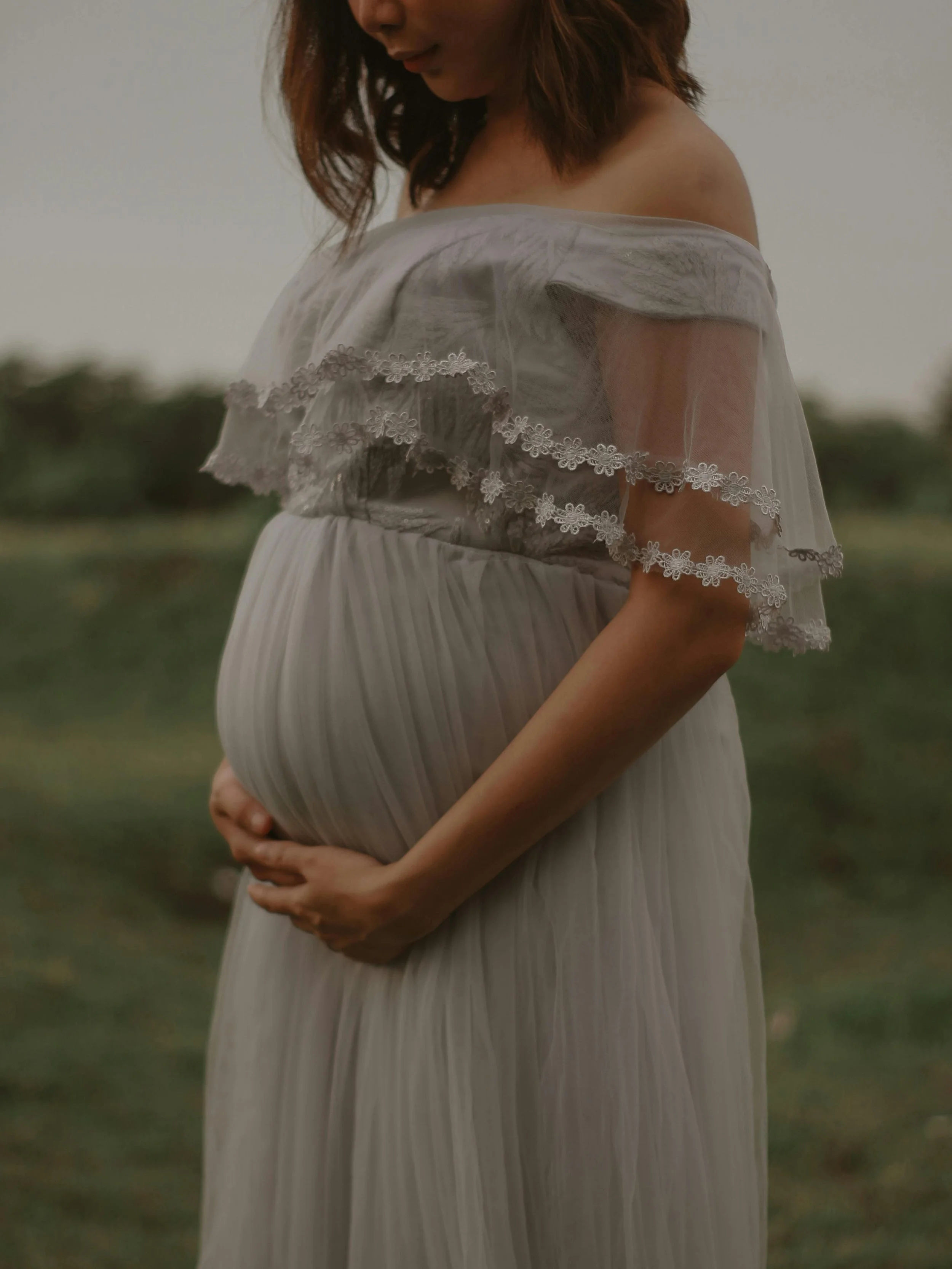 A pregnant woman in Portland, Oregon holds her stomach, feeling confident in hiring Wildflower Doula Services for her newborn care.