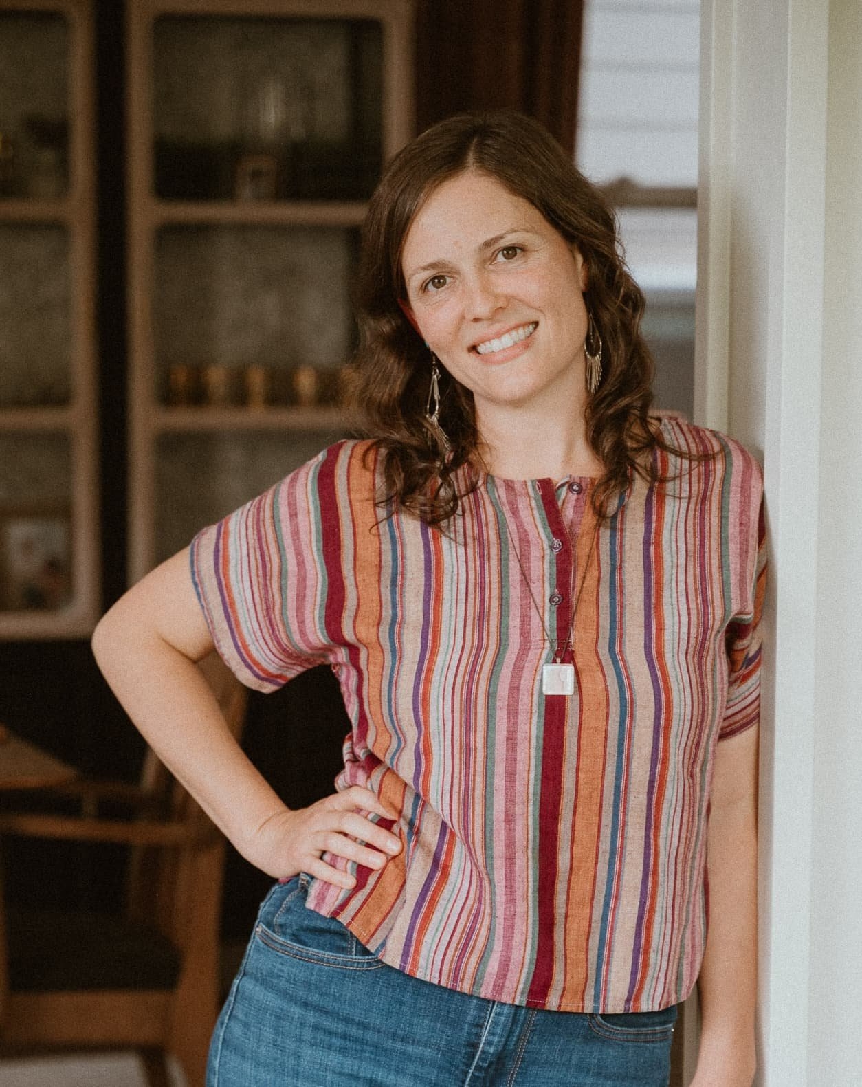 Expert postpartum doula and founder of Wildflower Doula Services, Julia-Rose Scianna, smiles in a striped shirt.