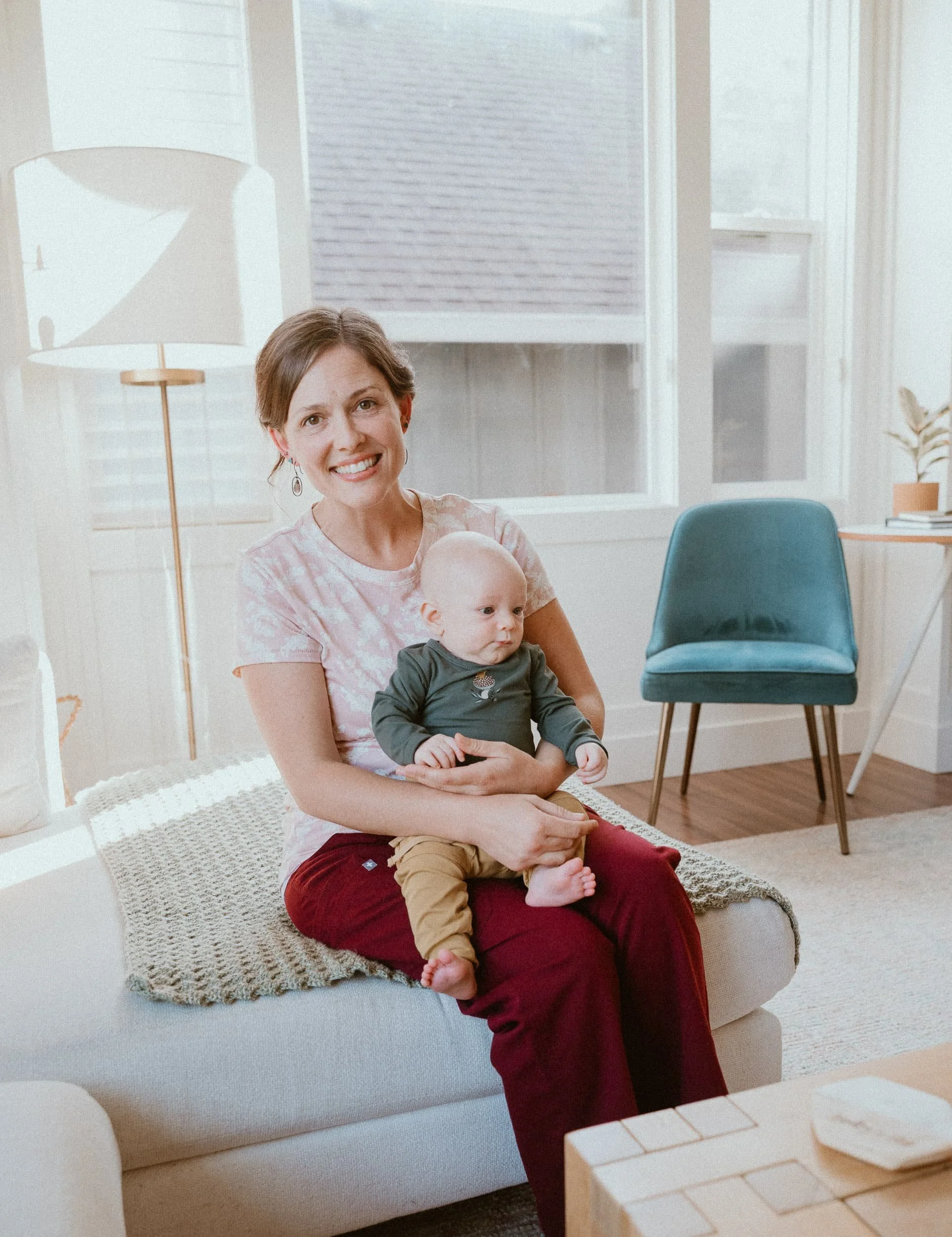 Sleep consultant and founder of Wildflower Doula Services, Julia-Rose Scianna, smiles while holding a baby.