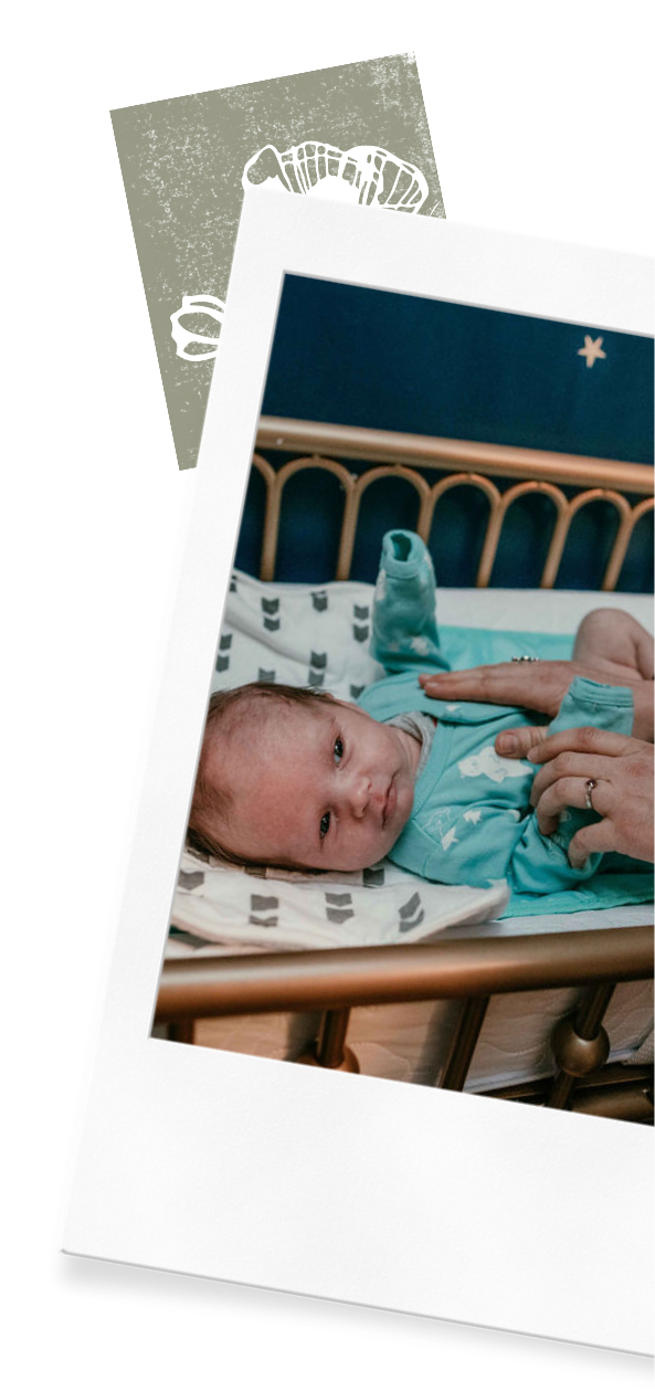 A parent who uses Wildflower Doula Services sleep consulting service in Oregon coos at their baby in a crib.