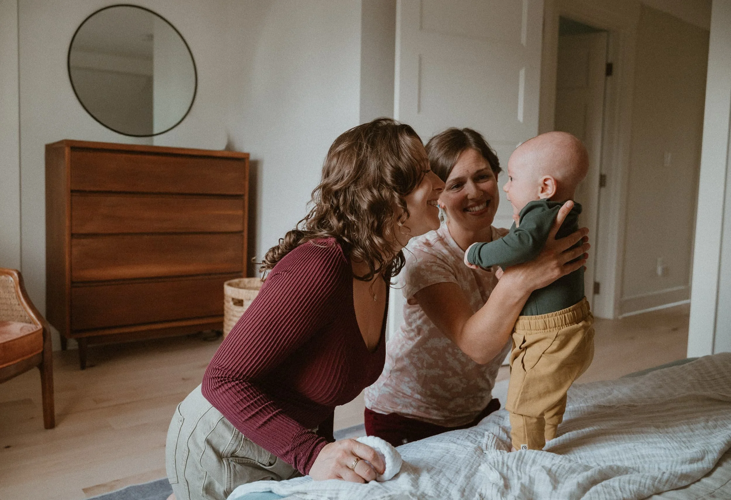 Julia-Rose Scianna, newborn care specialist, smiles while holding a baby in Portland, Oregon.