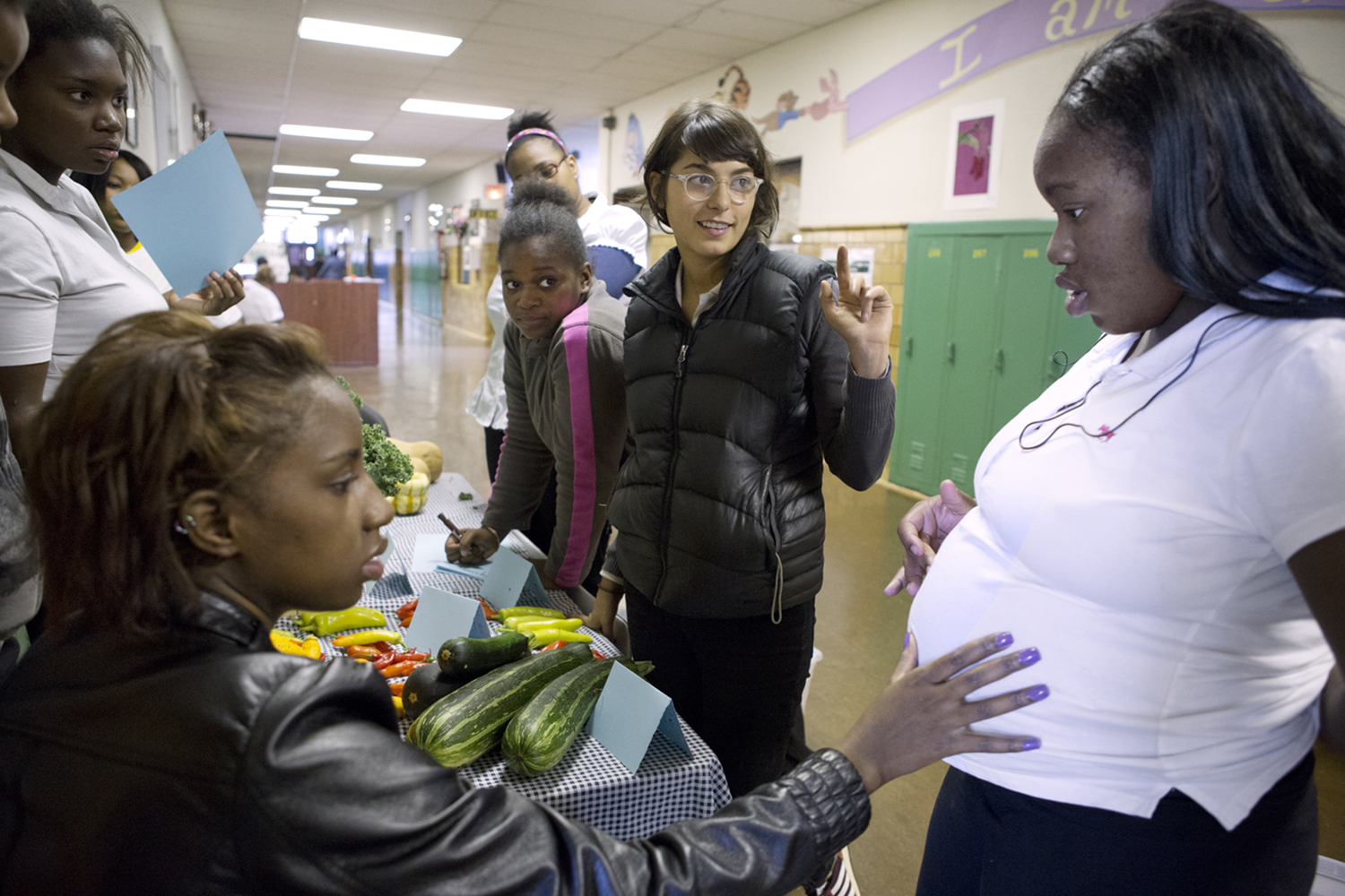 Dana Applebaum, center, farm educator at Catherine Ferguson Academy, pauses as Kanisha Miller touches Shantanique Dixson's belly during a farmers market at the school. CFA has been open since 1986 and is designed for young mothers and expecting mothers trying to finish high school in Detroit. The school has since closed.