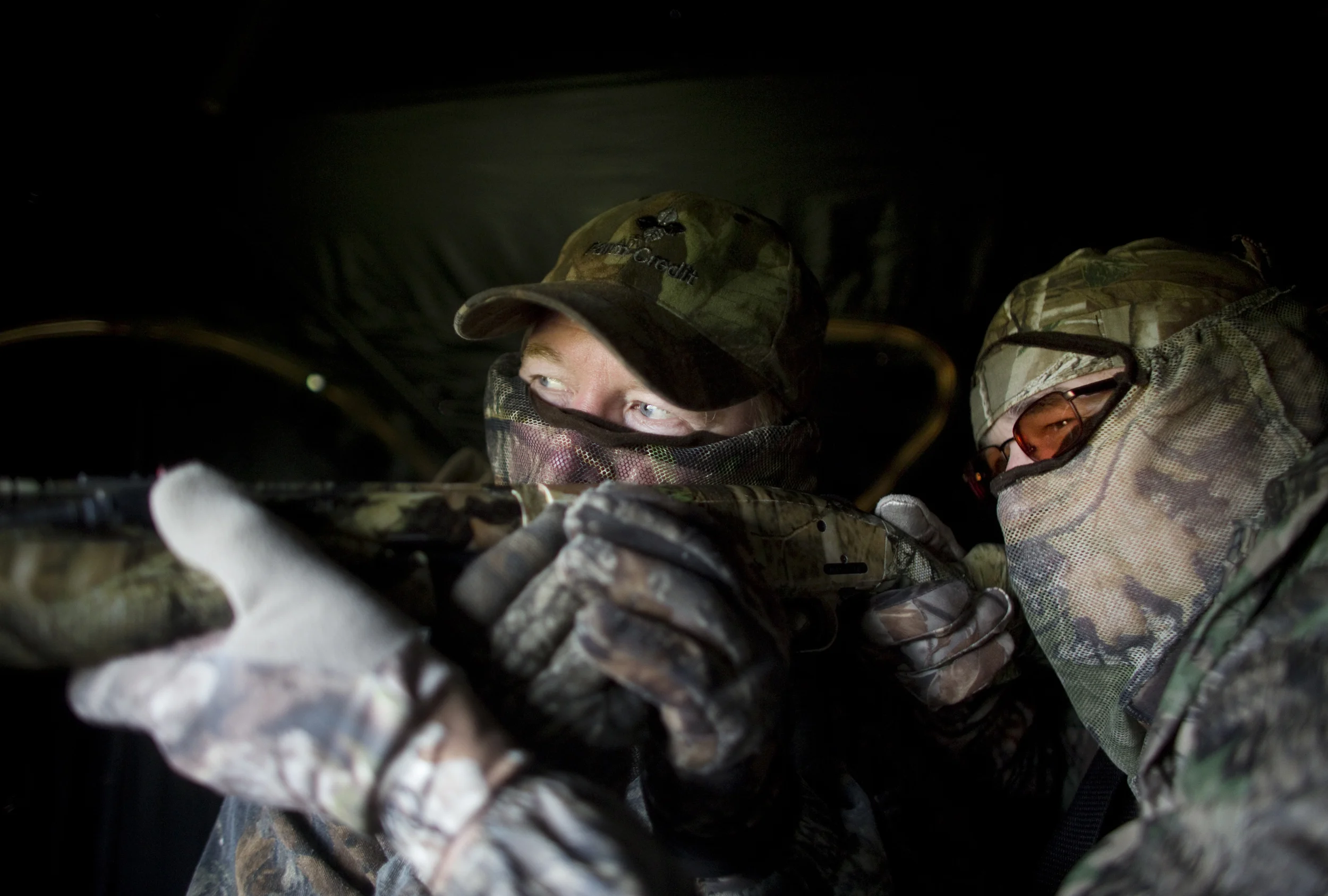 Tommy Meador, left, one of the two sighted guides, looks down the barrel of Mike Doyle's gun and helps point the Mossberg 500 shotgun towards the decoys as Doyle, right, also keeps his eyes open as they sit inside of a ground blind practicing during their hunt. Meador has helped out with the hunt for the past six years. 