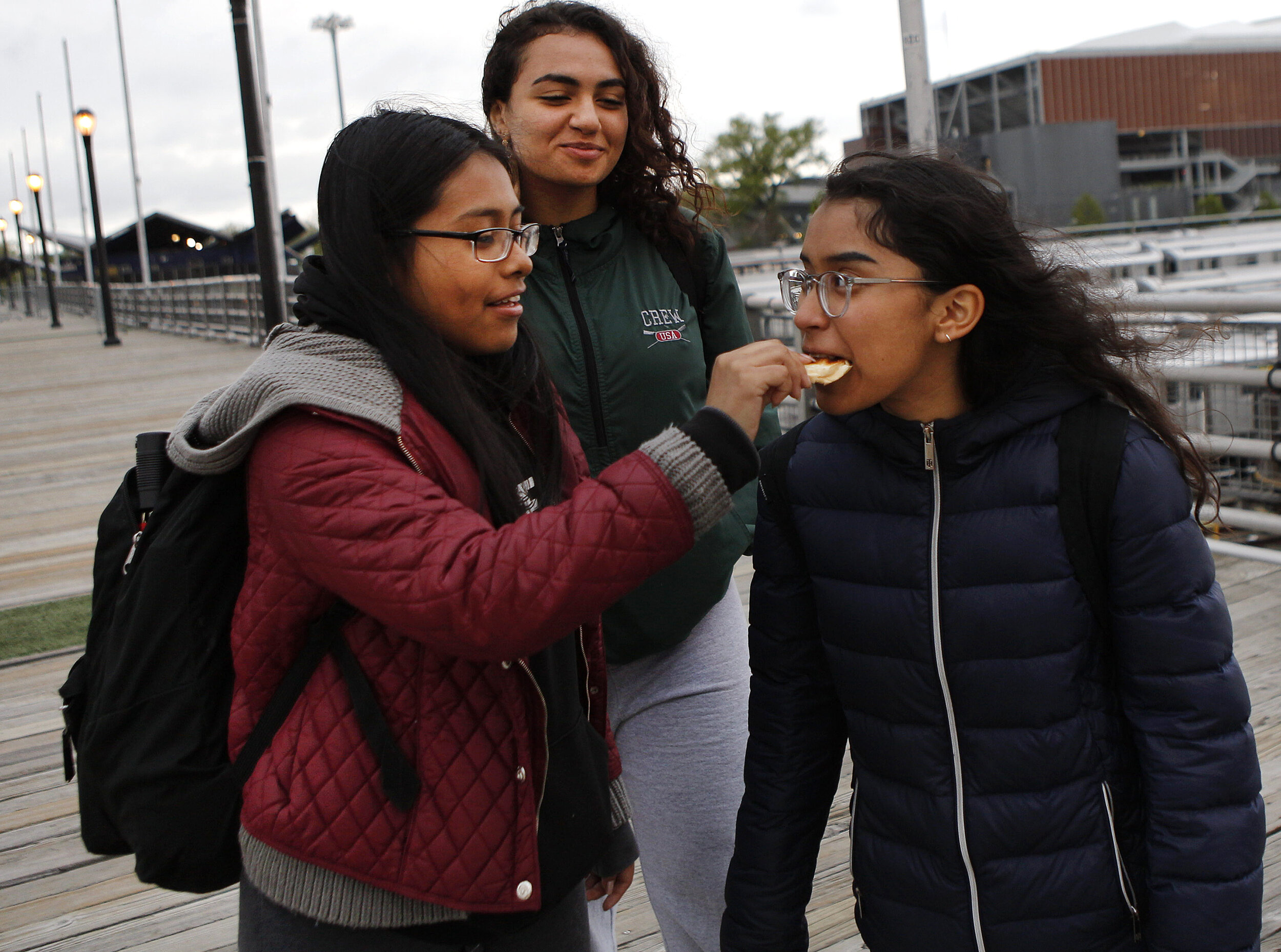  Sebastiana Lopez, 17, left, feeds a snack to her teammate Ix’Chel Angeles, 16, right, as Salma Youssef, 17, center, walks with them back to the 7 subway train at Willets Point after rowing practice on Thursday, May 2, 2019 in Flushing Meadows Corona