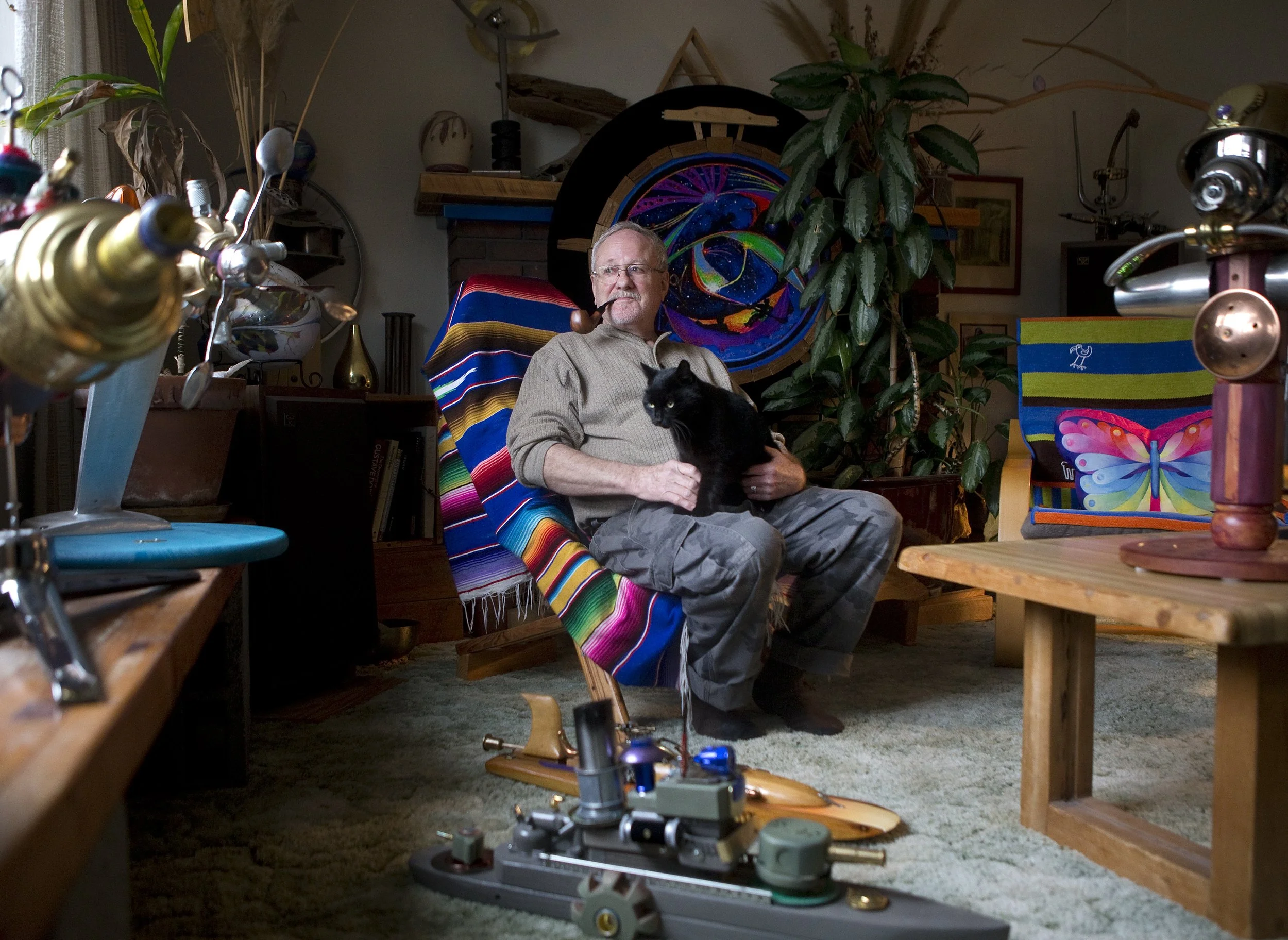  Artist Steve Okerman, 73, sits in his living room with his cat Kiwi and several of the pieces he has created. Okerman was once a locomotive engineer for 34 years. "Art has always been in me," he said. He found many parts of his art pieces while work