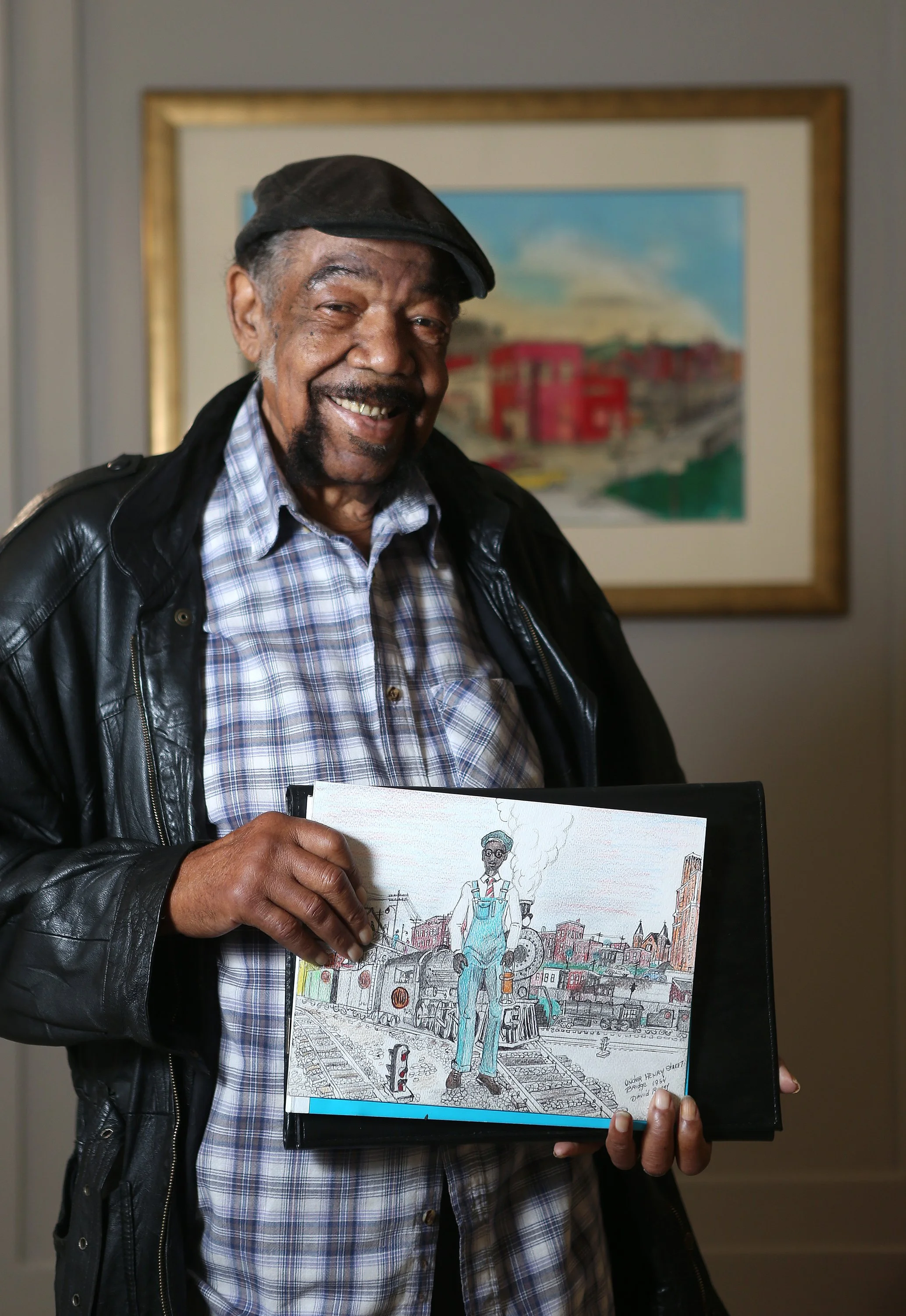  David Ramey holds one of his drawings in the works while standing in front of a framed piece that was purchased by the Roanoke Arts Commission, now hanging at City Hall. Hanging on the wall is a colored pencil drawing called "Henry Street" made in 2