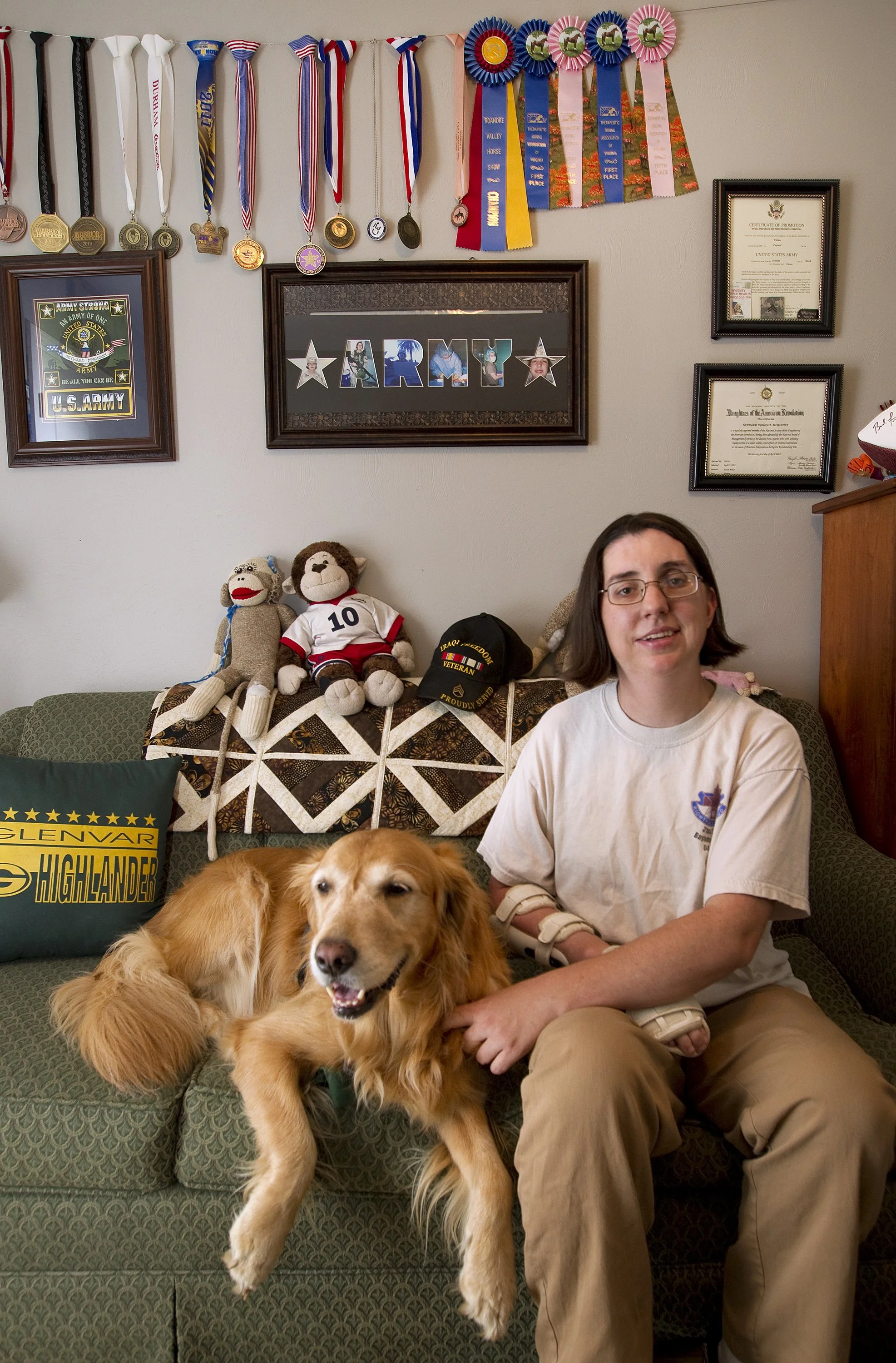  Seyward McKinney, 33, served in the Iraq war as an operating room technician. McKinney sits with her service dog, Whitney, in her home where medals that she's earned from various competitions that involve skiing, horse back riding and biking on her 