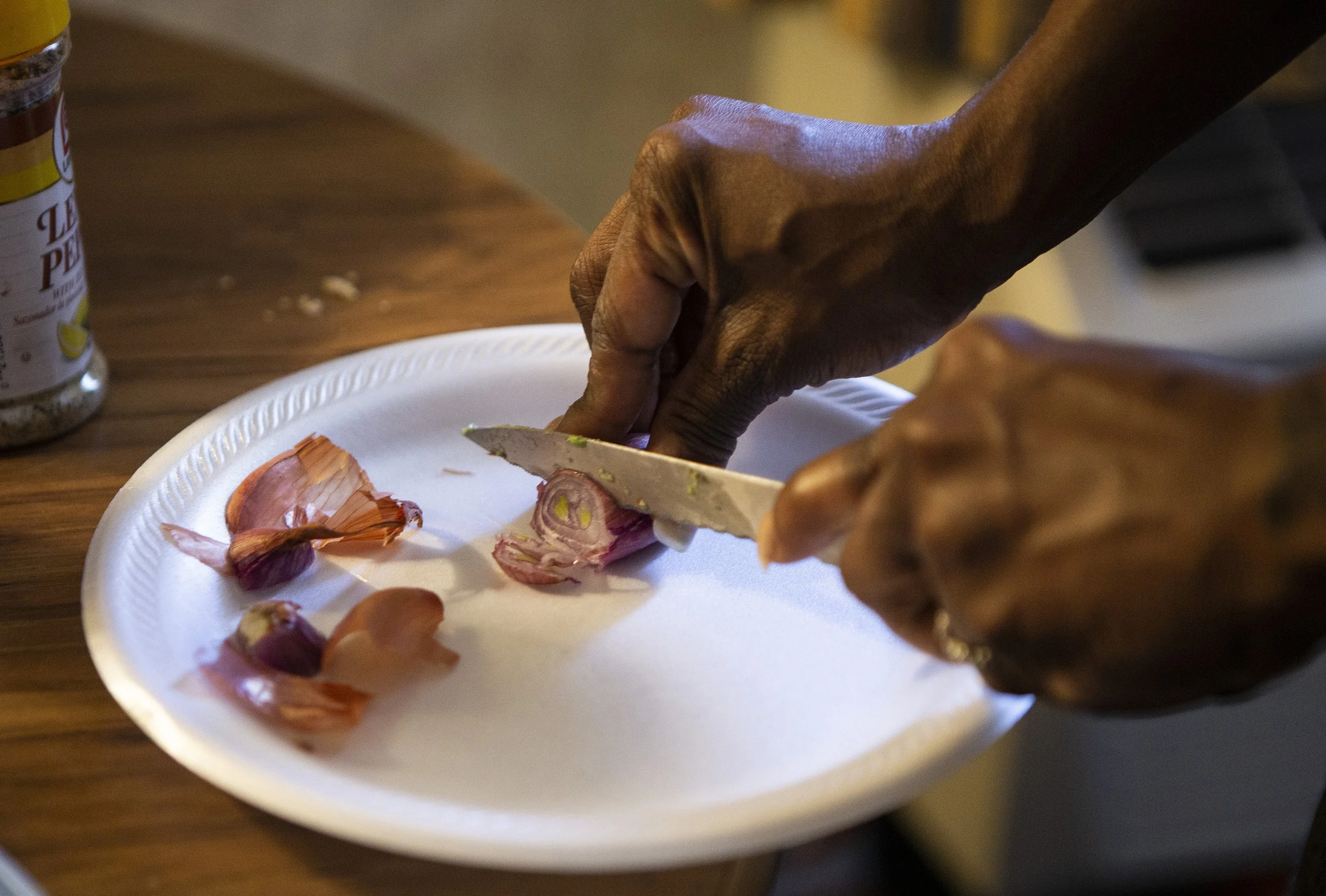  April Goode chops shallots on a styrofoam plate while cooking hamburgers for lunch in a hotel room with her children on Saturday, March 7, 2020.  