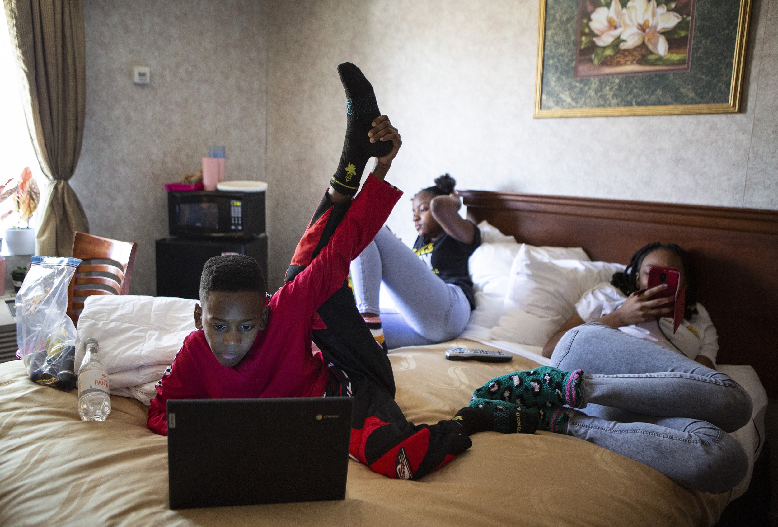  Ethan, 9, relaxes while playing a game on a laptop while his older sisters Miriah, 12, and Jazmyn, 14, also pass time on their phones on Saturday, March 7, 2020. Goode and her children have been living at the Quality Inn in Ledgewood, New Jersey for