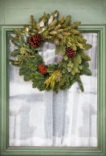 A nice evergreen wreath with a few small pinecones. Loving the color of that door, too!
